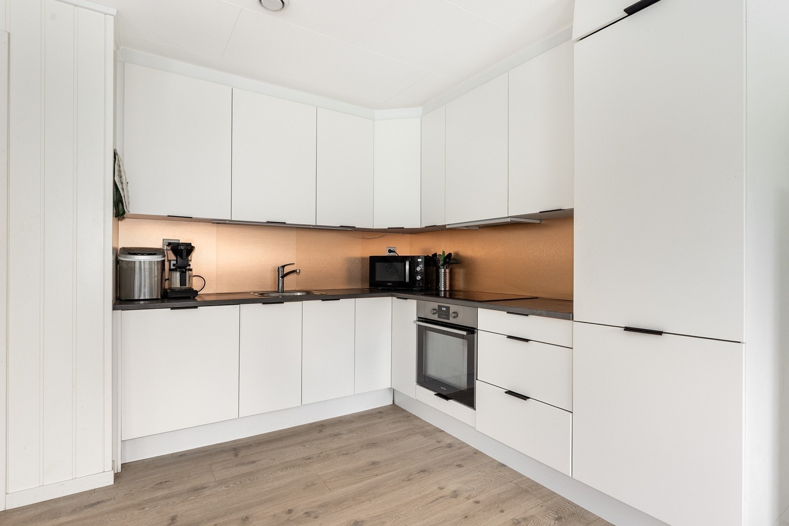 Fine detaljer hvor kjøkkenet er foret helt opp til tak og mot vegg Galleribilde