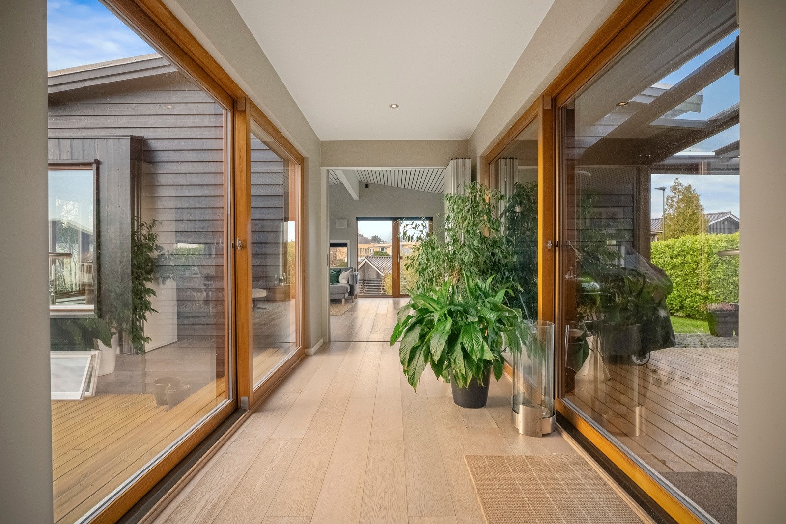 Mellom stue og kjøkken finner man en smakfull glassgang med utgang til terrasse på den ene siden og til hagestue på den andre. Galleribilde