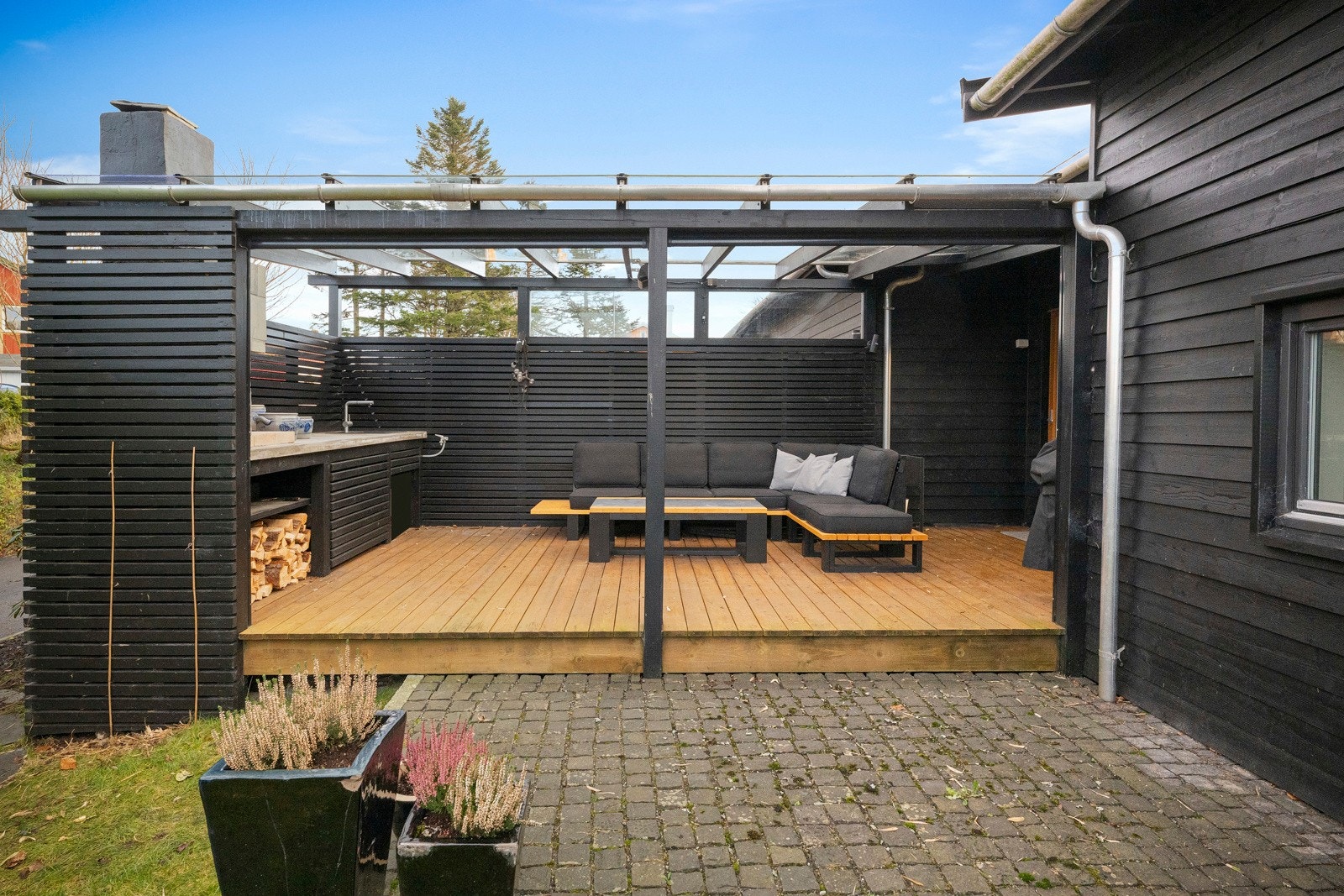 På baksiden av boligen finner man et svært trivelig uteområde med takoverbygg, peis og en praktisk benk med vask. Galleribilde