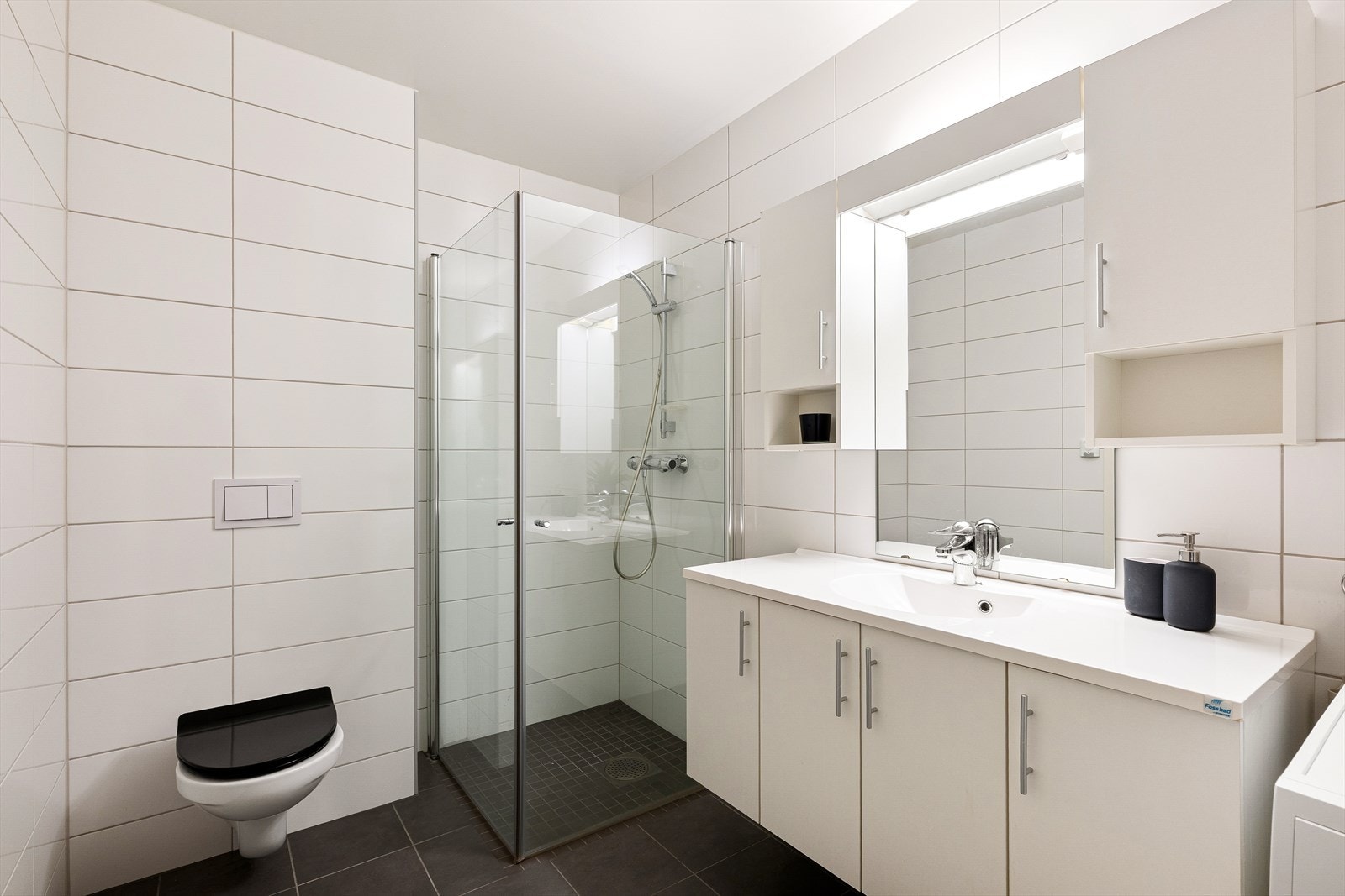 Flott flislagt bad med dusjhjørne i glass, vegghengt toalett og vannbårenvarme. Galleribilde