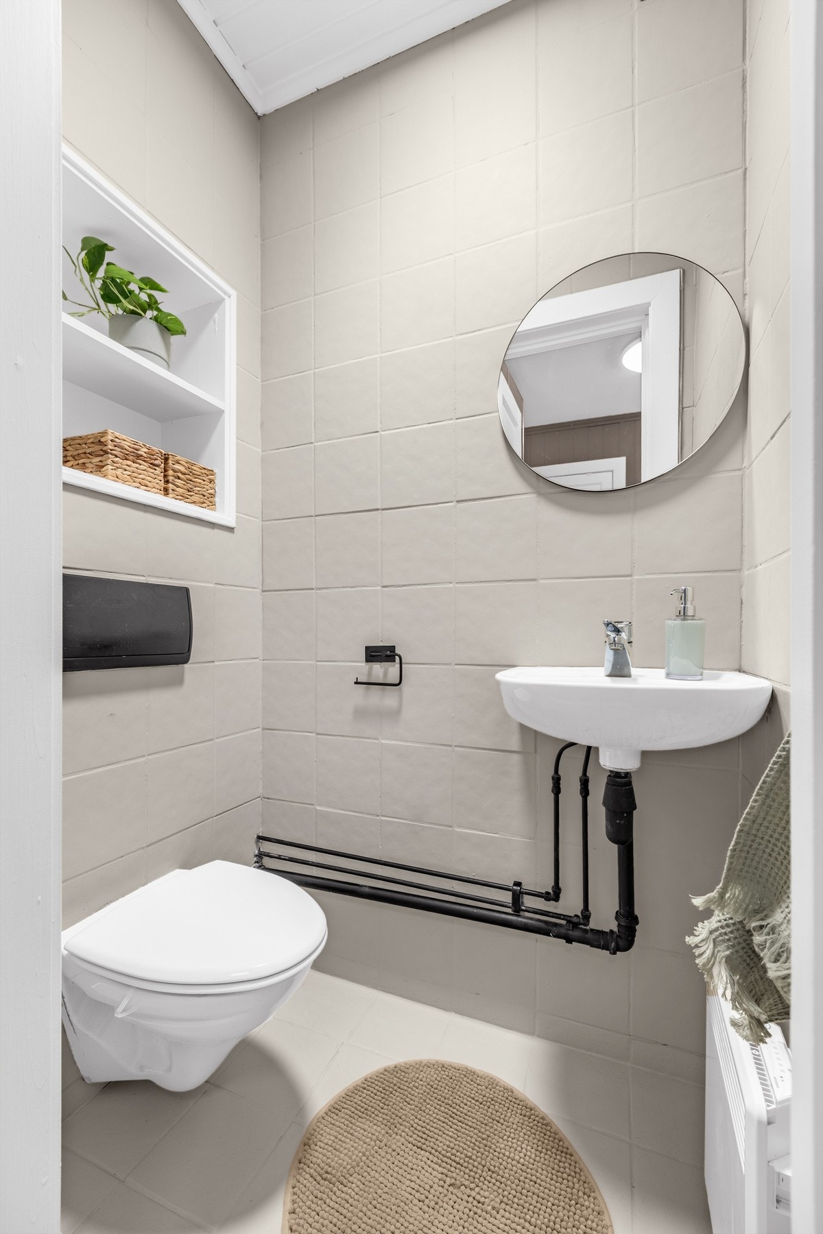 Toalettrom med flislagt gulv, vegghengt toalett, servant med blandebatteri, speil samt naturlig ventilasjon. Galleribilde