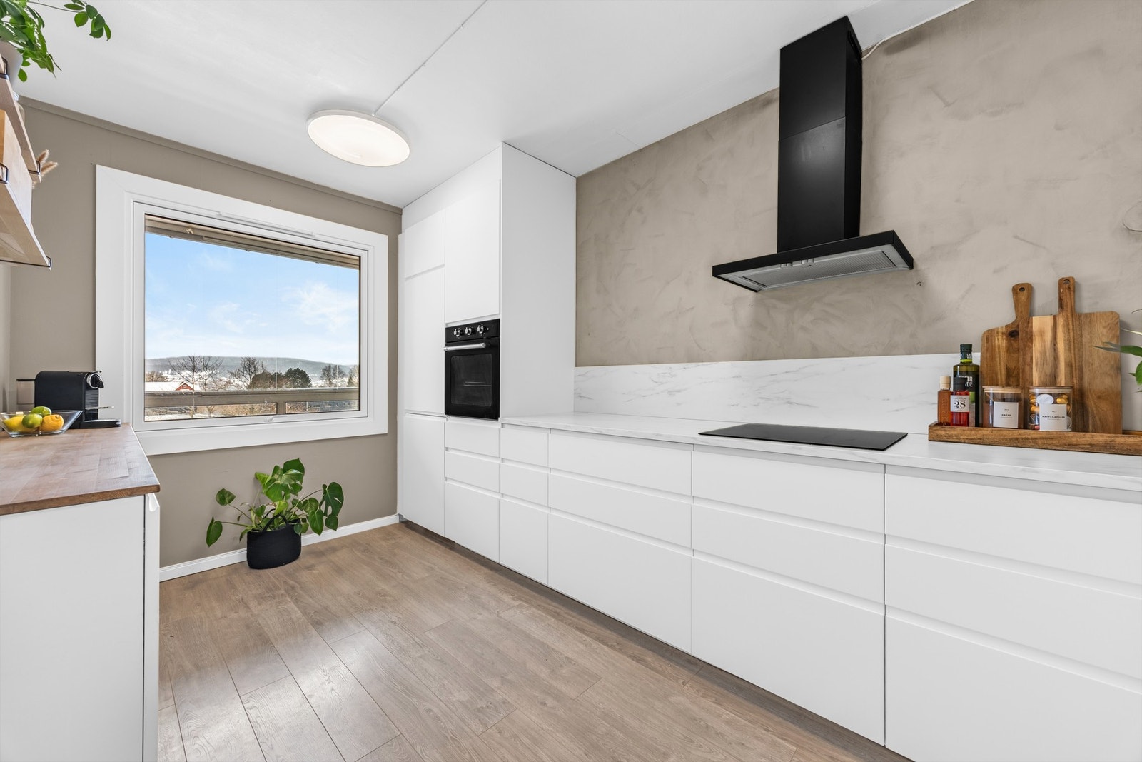 Praktisk arbeidskjøkken med integrerte hvitevarer og romslig benkeplate som gir gode arbeidsforhold i hverdagen. Galleribilde