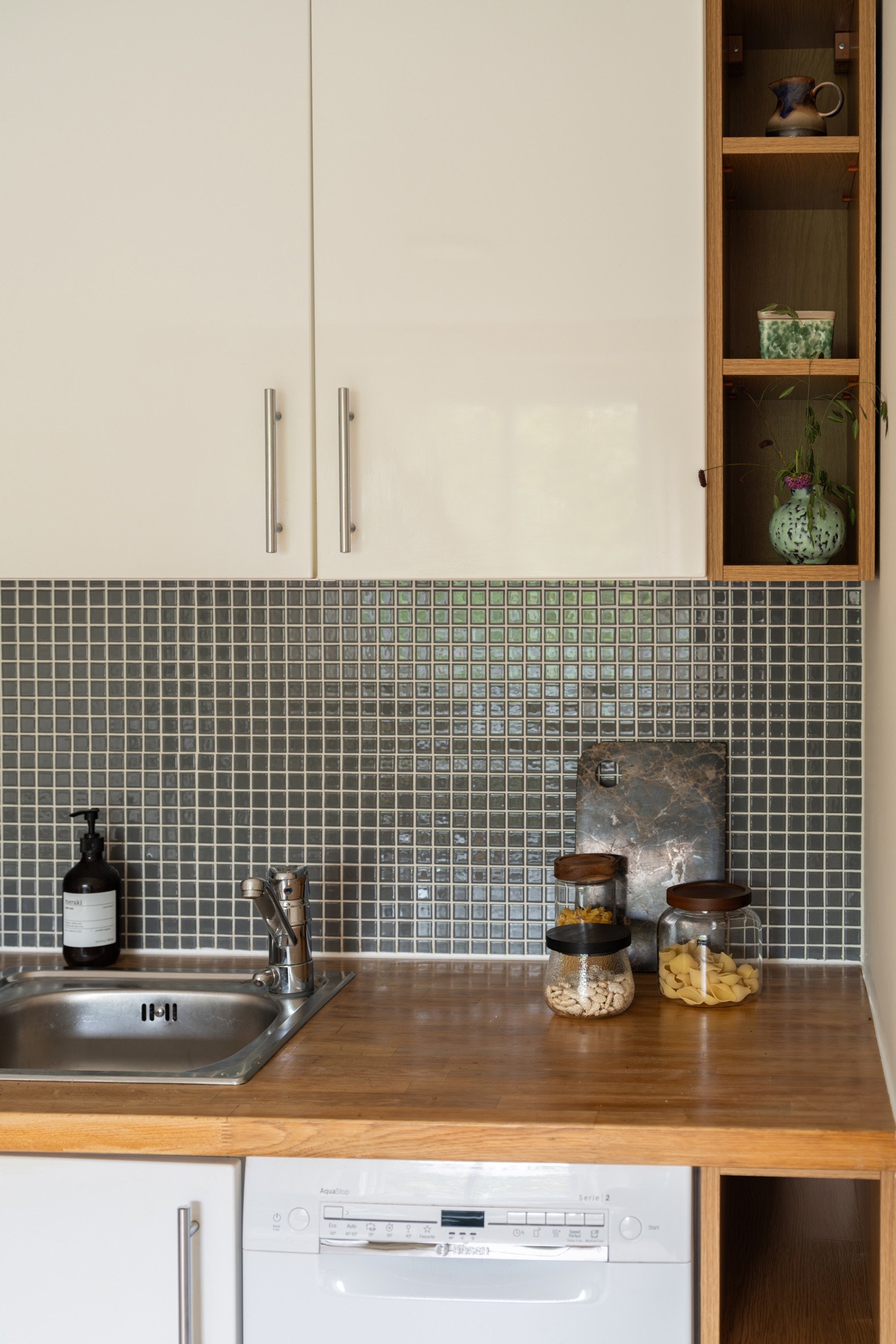 Både fine og praktisk med mosaikkfliser i benkeryggen. De åpne trehyllene gir et ryddig og helhetlig uttrykk. Galleribilde