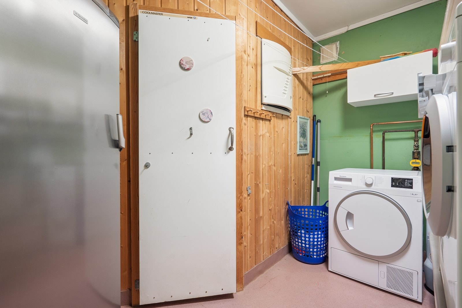 Videre finner man et praktisk vaskerom innredet med belegg på gulv og malte veggflater. Rommet er ellers utstyrt med utslagsvask, varmtvannsbereder og opplegg for vaskemaskin. Fra vaskerommet har man også tilkomst til et kjølerom. Galleribilde