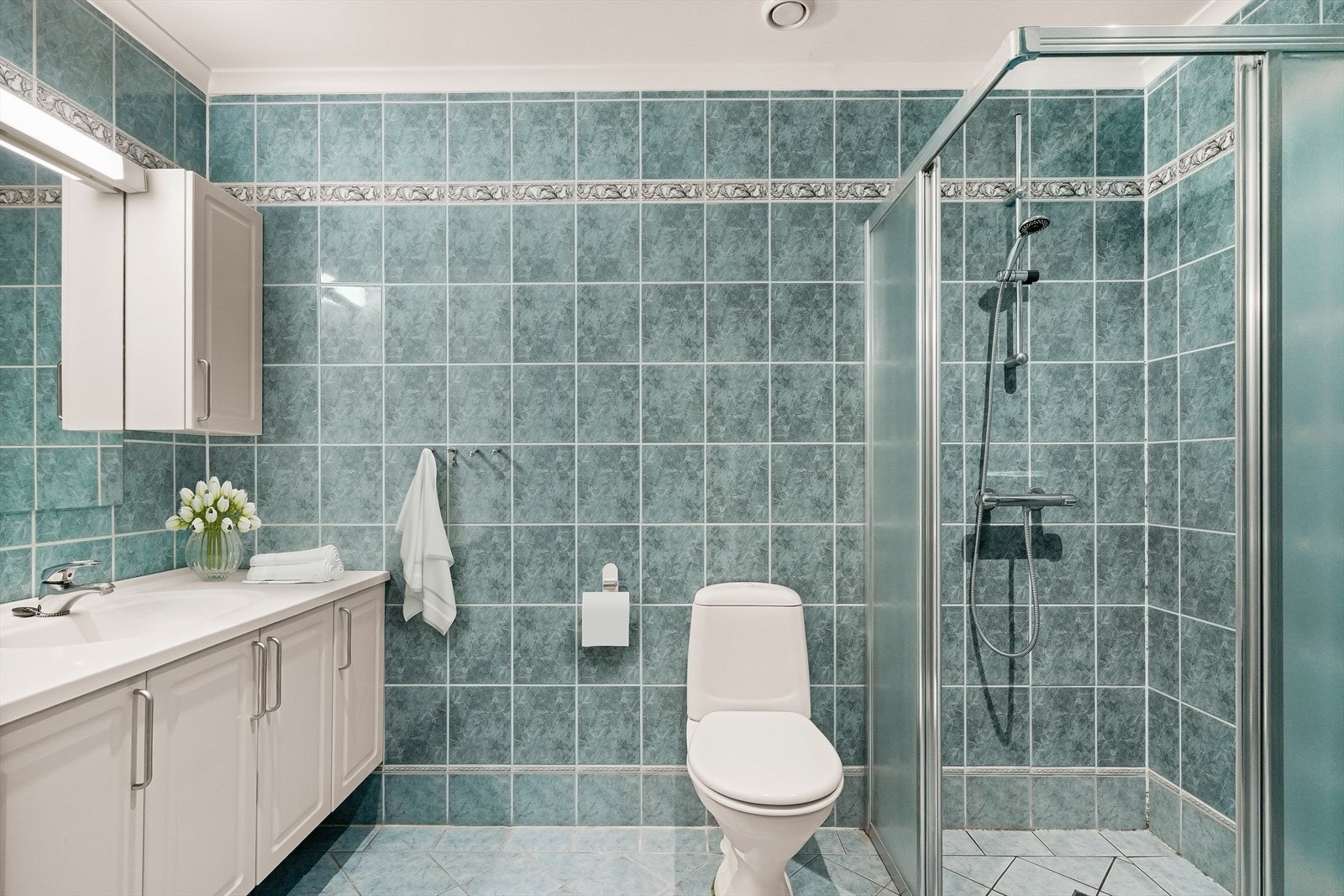 Badet er innredet med dusjhjørne, servantskap, speil, to overskap, høyskap og klosett. Galleribilde