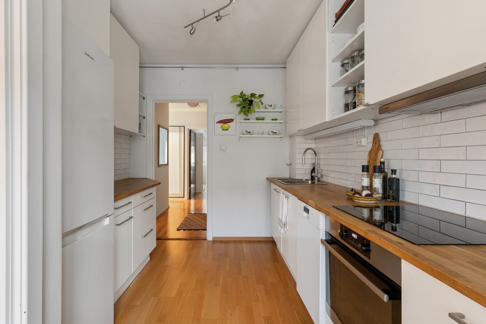 Lyst og tradisjonelt kjøkken med godt med skap- og benkeplass på to sider av rommet. Galleribilde