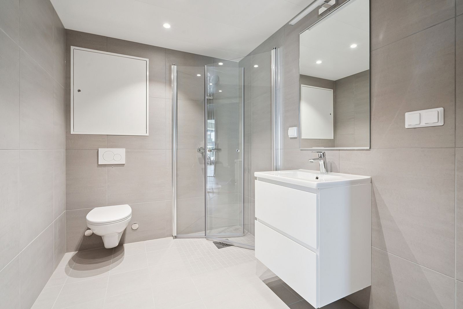 Delikat bad med dusjhjørne i glass og vegghengt toalett. Galleribilde