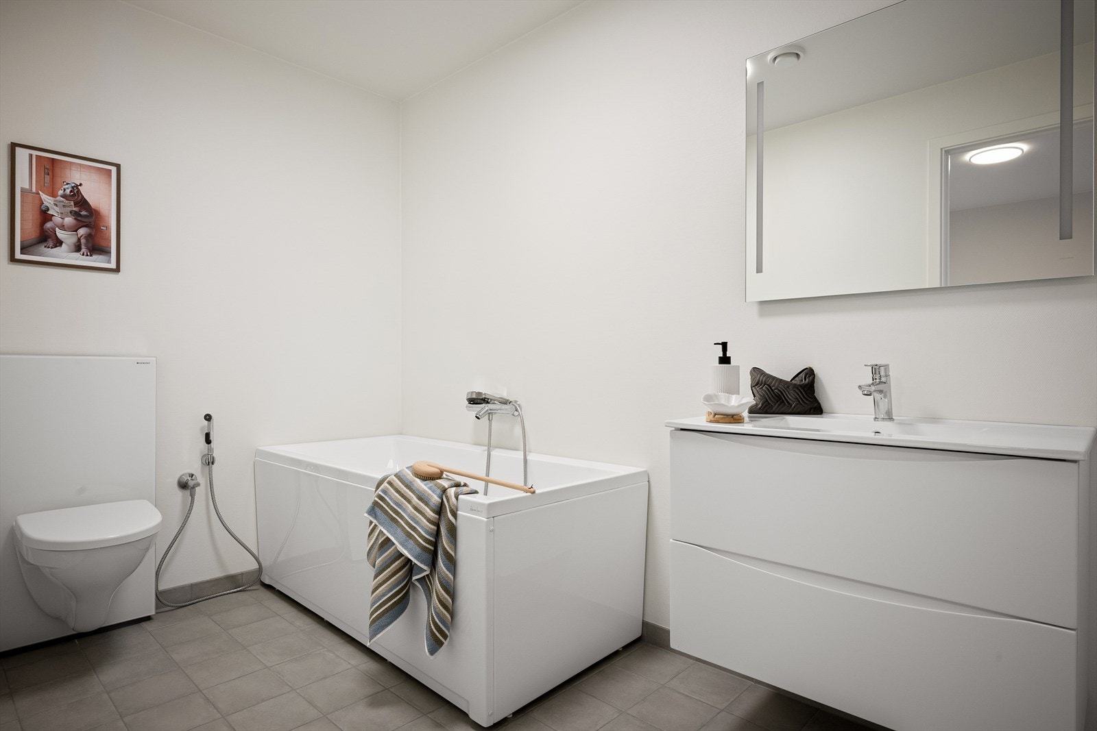 I denne etasjen er det i tillegg bod og husets bad nr 3. Badet med fliser på gulv og på vegger i dusj. Hvit seksjon med vask/benk. Badekar og vegghengt toalett. Galleribilde