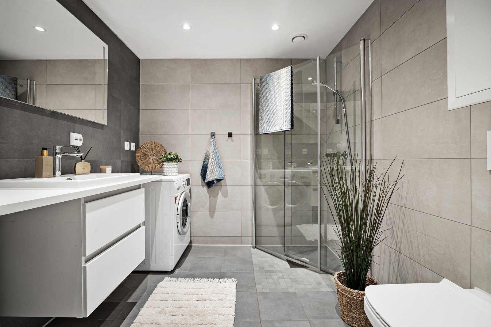 Delikat flislagt bad med dusjhjørne, innfellbare dusjdører og opplegg for vaskemaskin m.m. Galleribilde