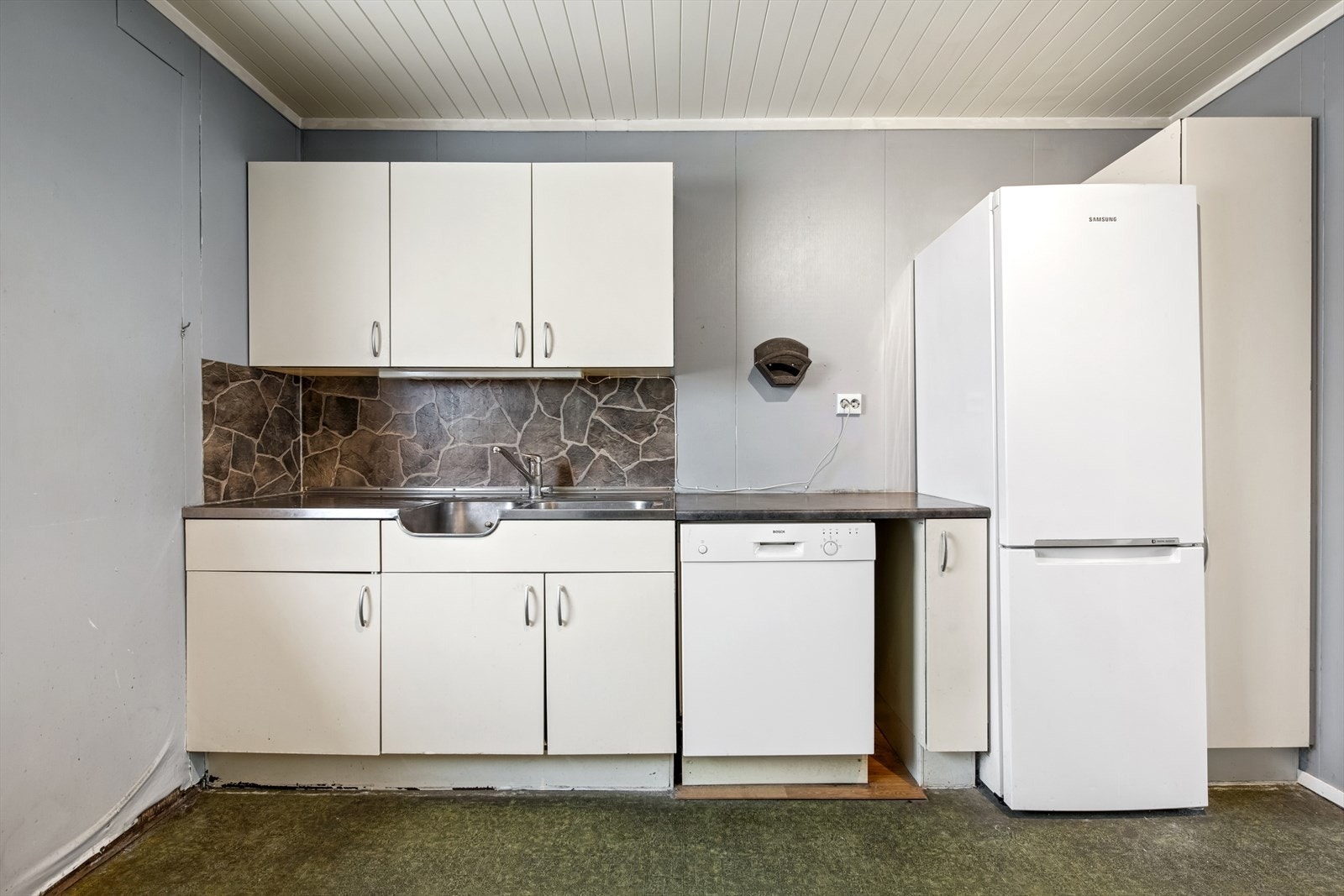 Kjøkkenet har en innredning med glatte fronter, laminerte skrog og en benkeplate som er en kombinasjon av heldekkende beslag og laminat. Galleribilde