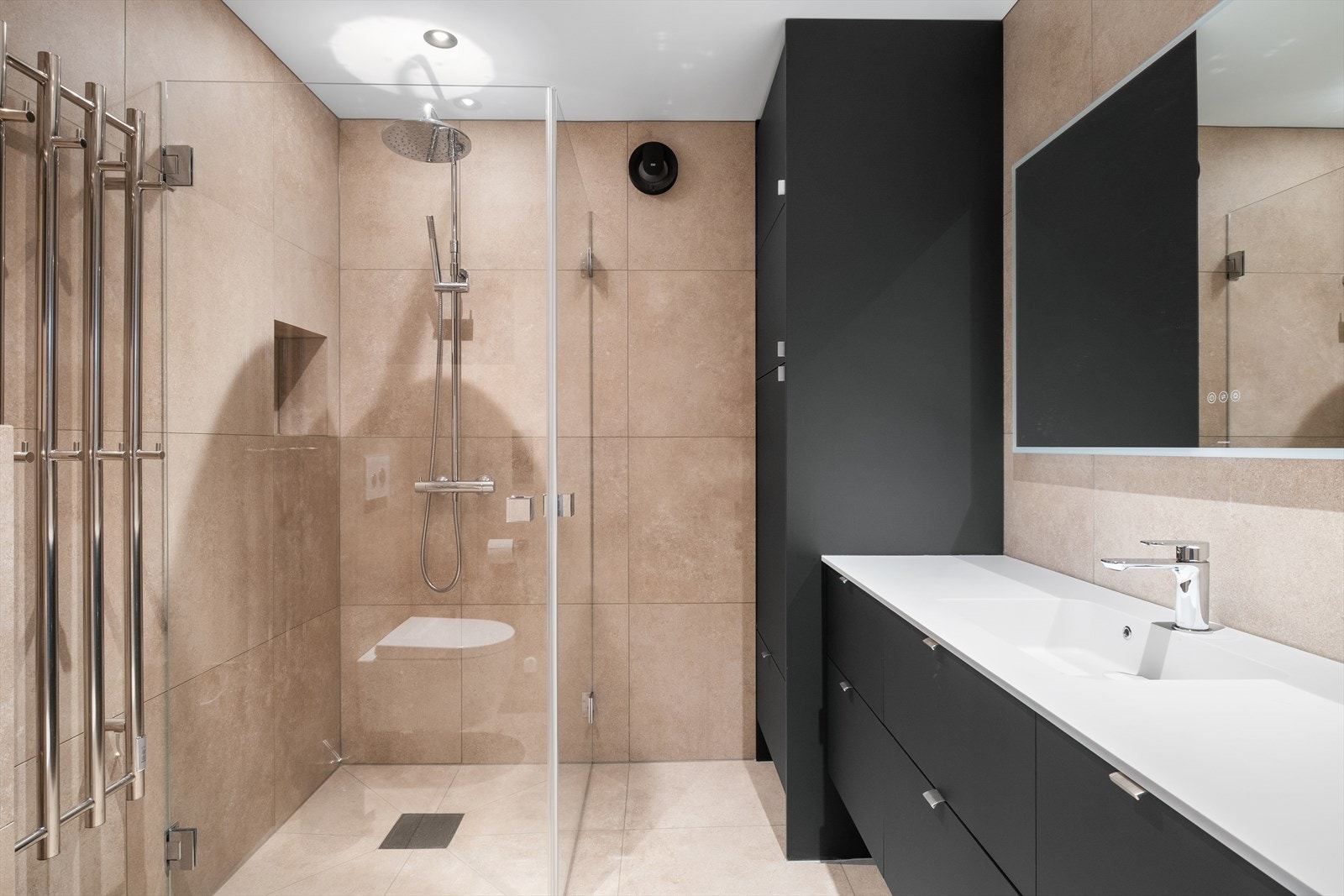 Baderommet har stilrein møbelinnreiing frå Aubo med nedfelt servant og underskuffer, integrert Electrolux vasketørkemaskin i skåpet, dusjhjørne med innfellbare glasveggar, og vegghengt toalett. Galleribilde