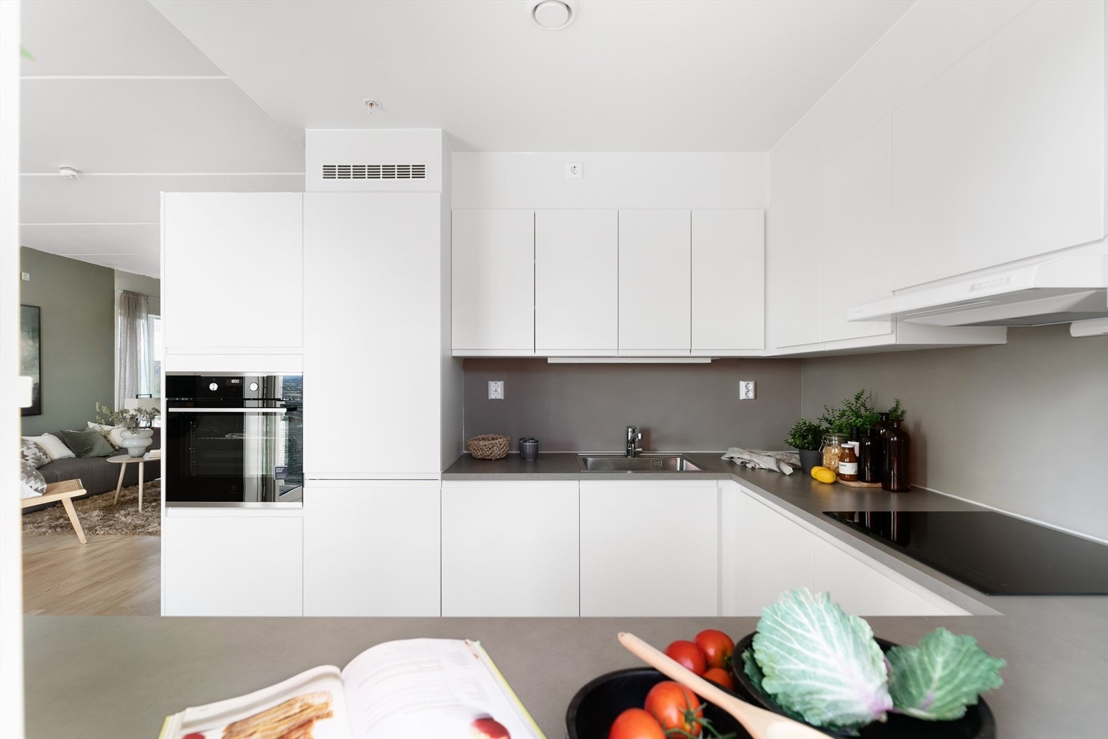 Stilrent kjøkken med hvite glatte fronter. En kontrastvegg som tar igjen fargen i benkeplaten og gir kjøkkenet en fin helhet. Galleribilde