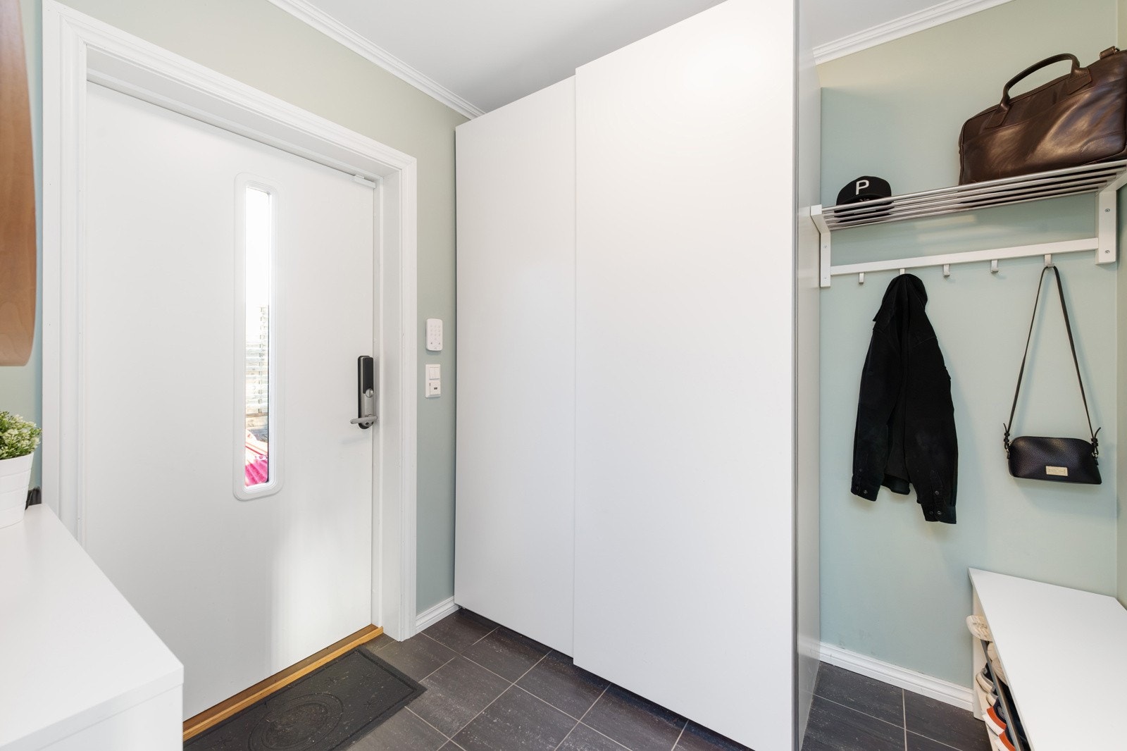 Dobbelt garderobeskap, kommodeløsninger og klesknagger, tilrettelegger godt for oppbevaring av uteklær. Galleribilde