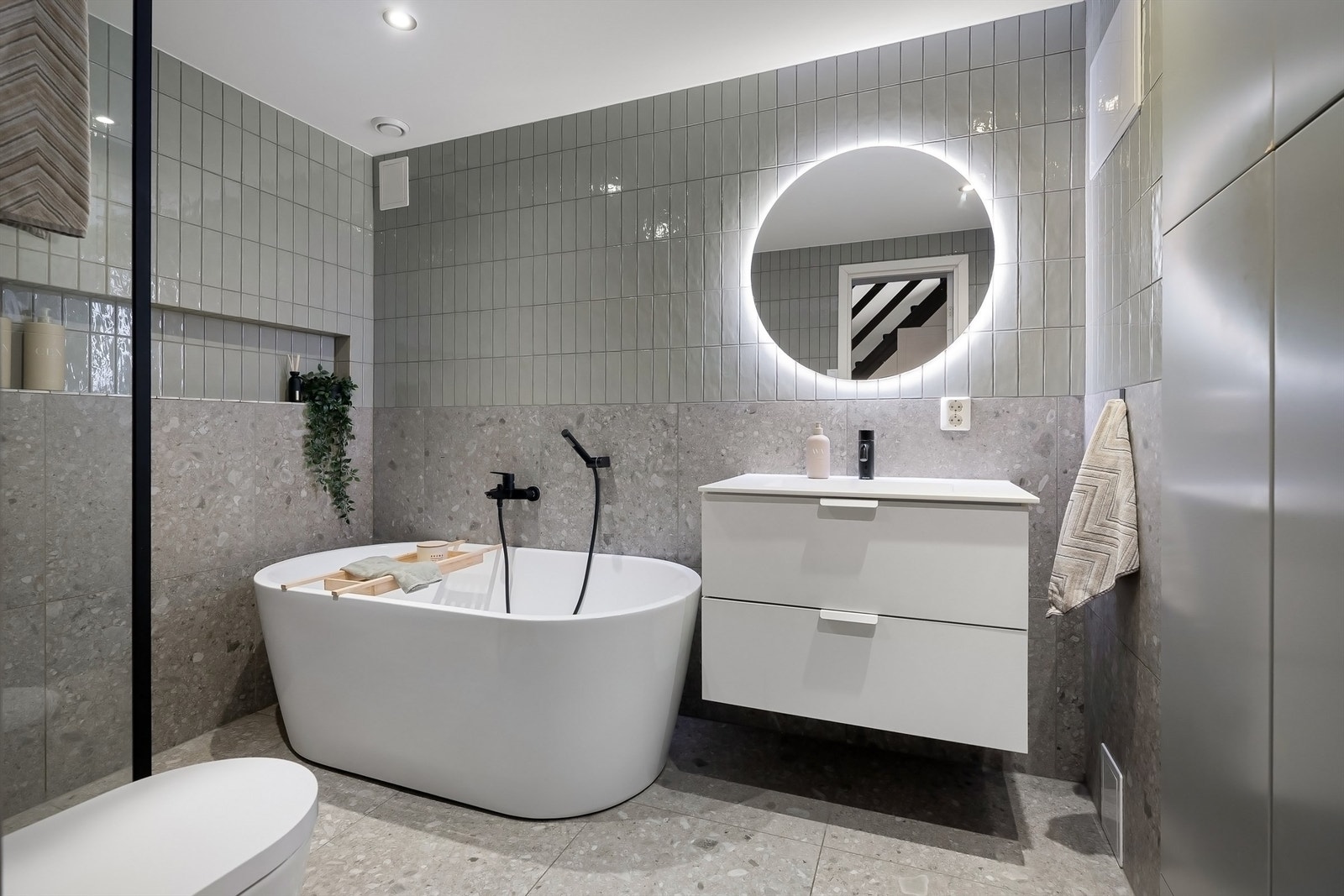 Delikat baderom fra 2021 med fliser på gulv med gulvvarme, fliser på vegger og malt himling med downlights Galleribilde