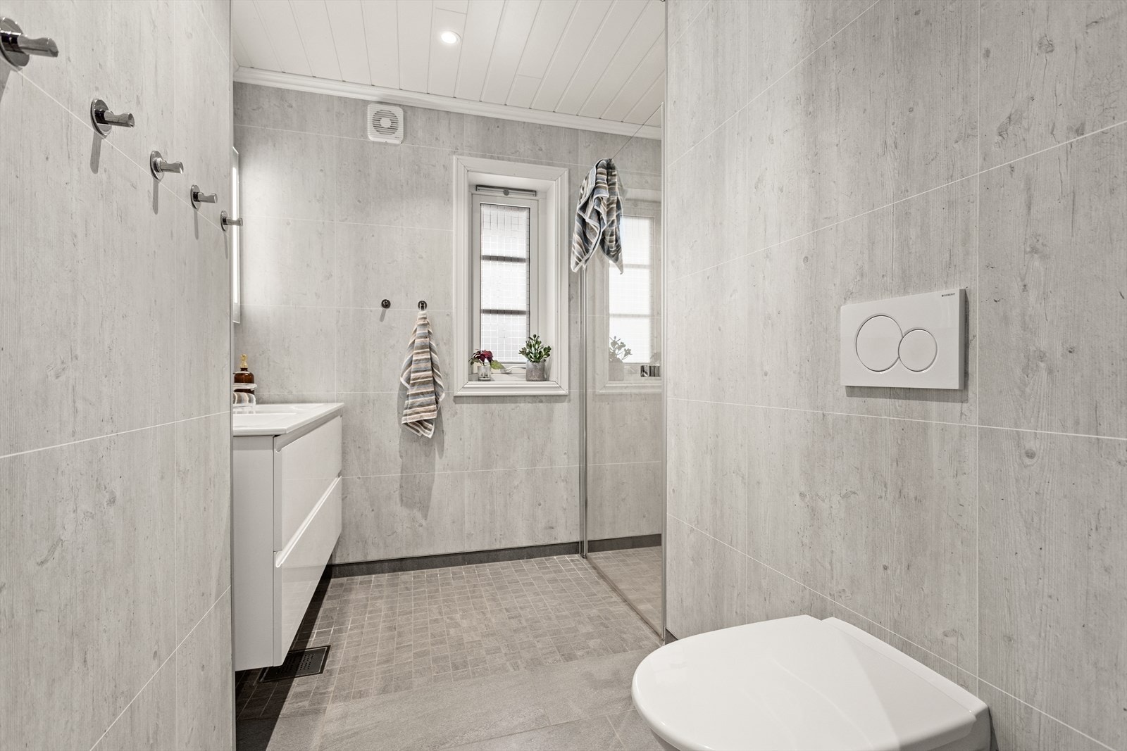 Romsleg bad i 1. etg. Innreiing består av dusjhjørne, dobbelt servant i innredning med underskuffer, spegel med lyslist og veggmontert klosett. Galleribilde