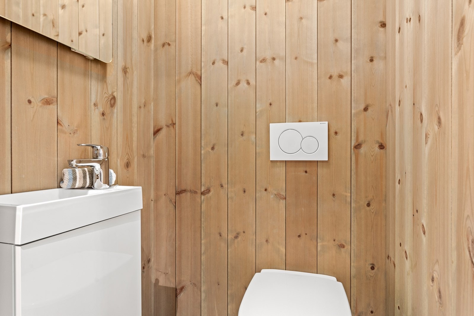 Praktisk toalettrom - eit ekstra toalett er alltid kjekt å ha! Det er flis på golv, panel på veggar og MDF-panel i taket. Her er det veggmontert klosett og vask i innredning. Galleribilde