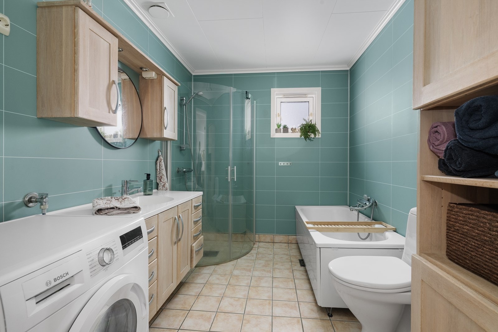 Badet med flislagt gulv og Fibo baderomspanel på veggene er av god størrelse. Her er det satt inn ny baderomsinnredning i 2022 med god oppbevaringsplass. Badet er også innredet med både dusjnisje og badekar, samt toalett og opplegg for vaskemaskin. Galleribilde