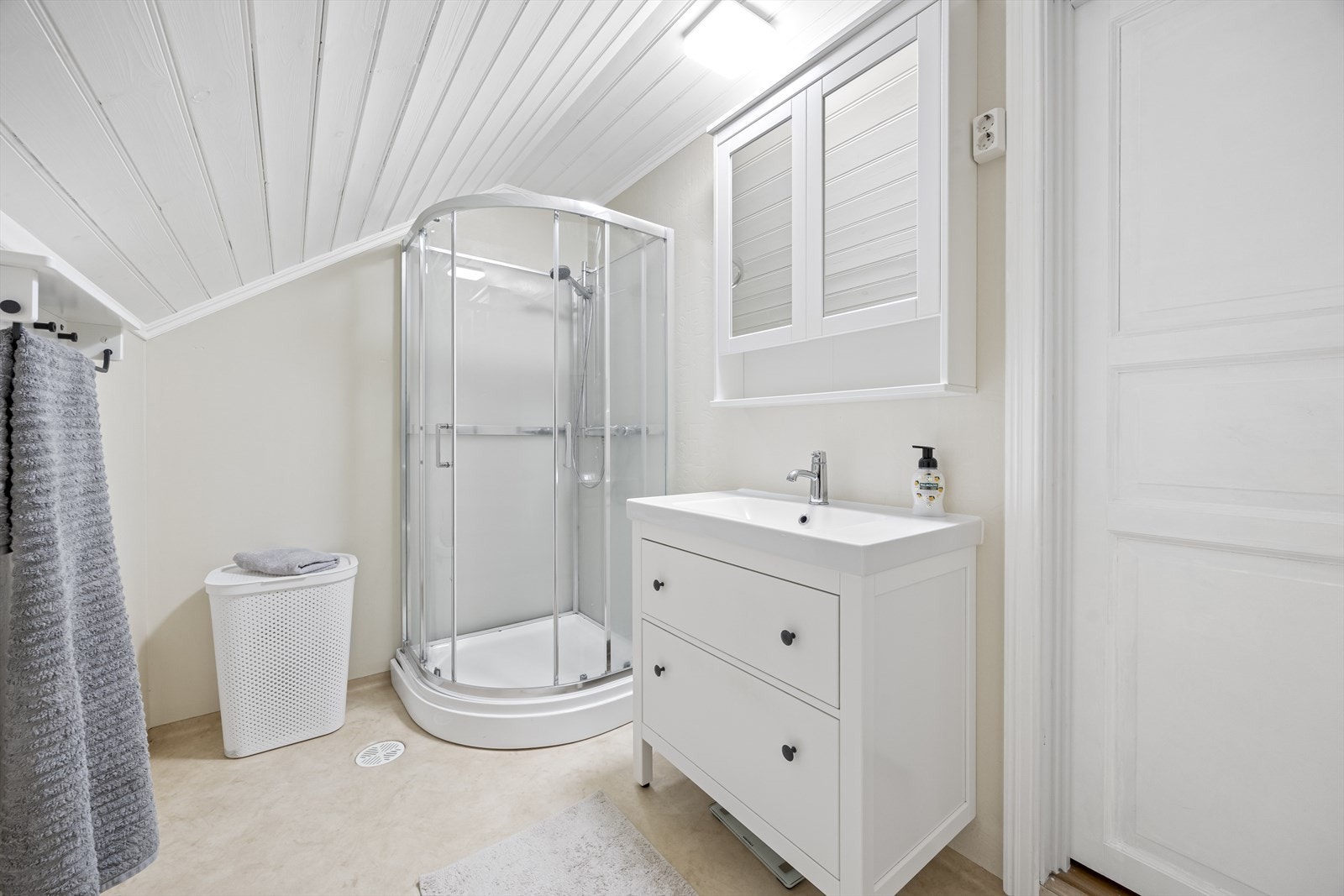 Badet har dusjkabinett og servant med underskap, samt panel i taket for en lys overflate. Galleribilde