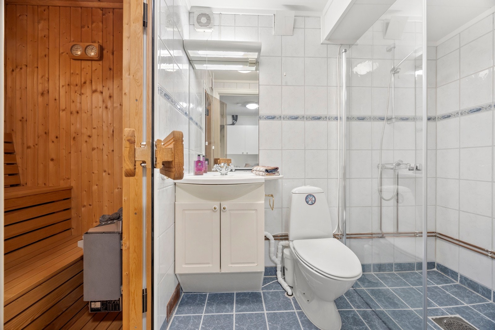 Badstue med panel på vegger og i himling, og tremmer på gulv. Bad med fliser på vegger og gulv med varmekabler, dusj, servant integrert i lys skapinnredning, speil og lys. Wc med kvern/pumpe. Galleribilde