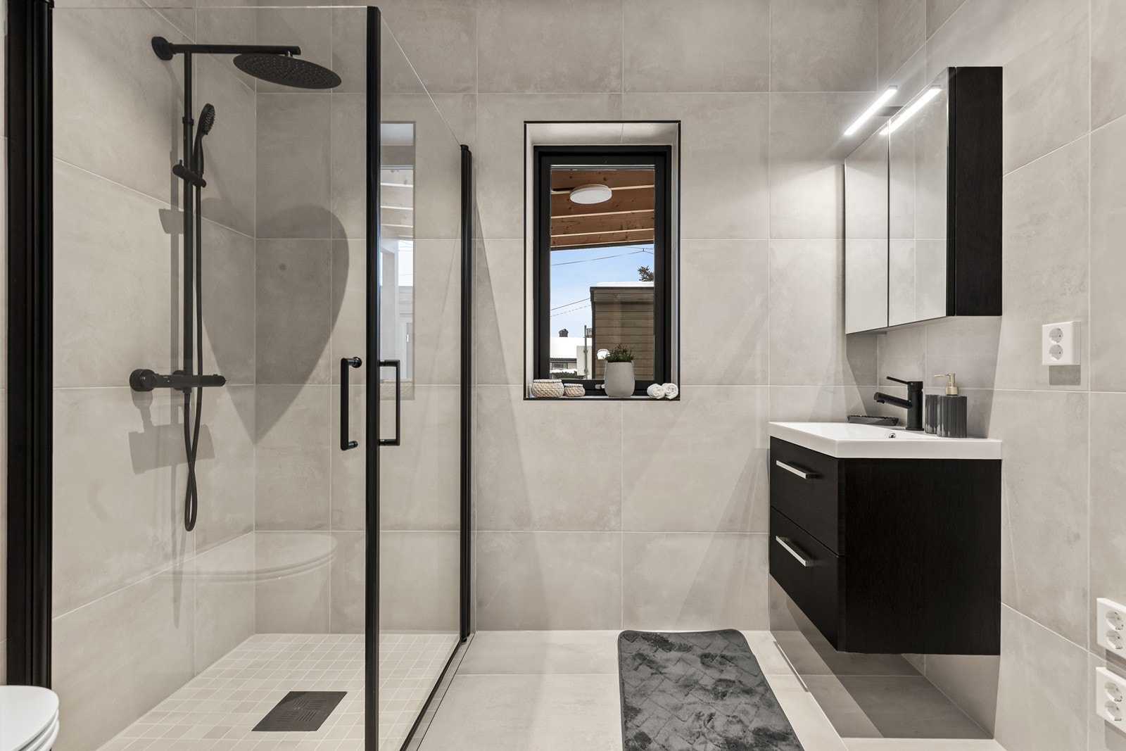 Badet i første etasje har en romslig dusjnisje med sorte profiler. (Bilde fra speilvendt bolig). Galleribilde