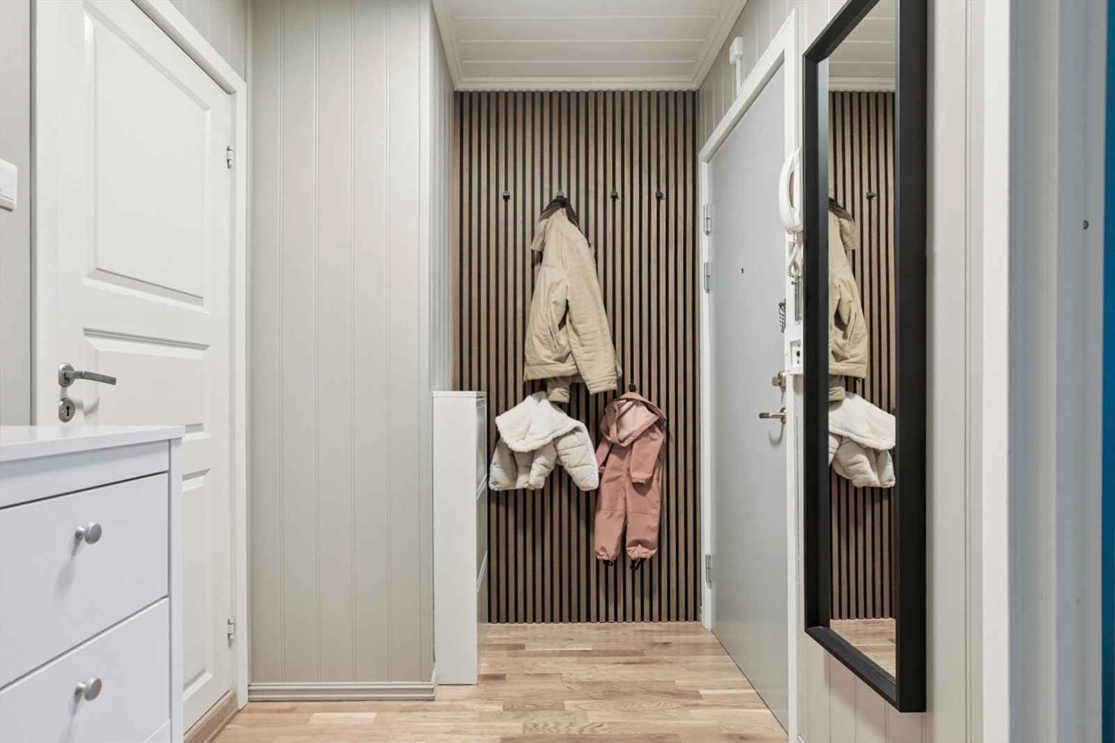 Entréen ønsker velkommen med en moderne spilevegg og plass til yttertøy. Galleribilde