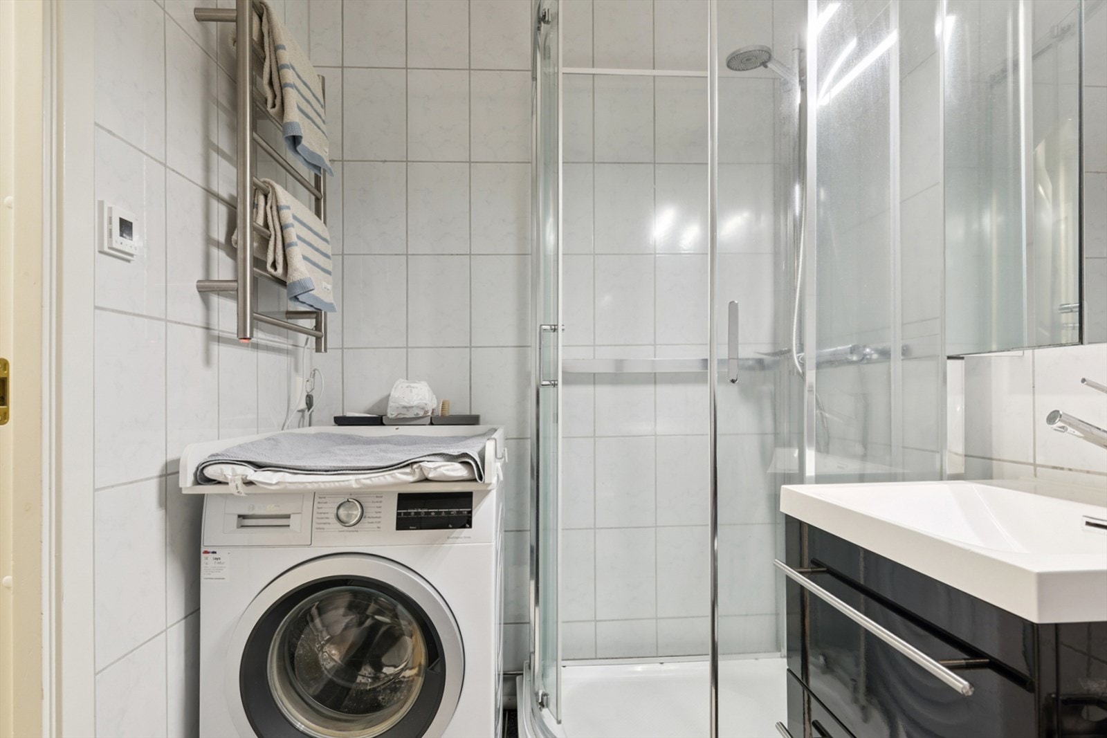 Her er det flislagte overflater, dusjkabinett og praktisk opplegg for vaskemaskin. Galleribilde