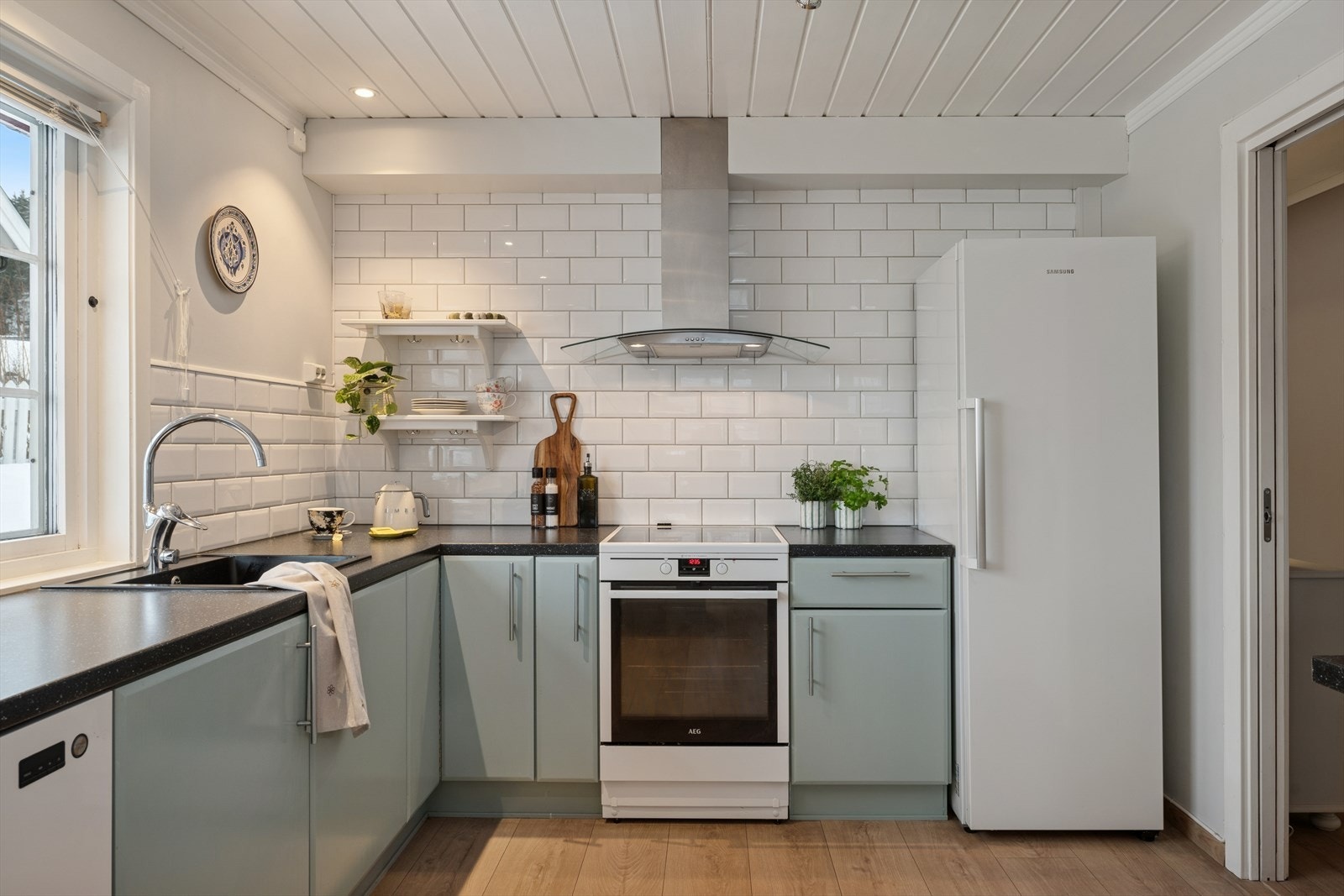 Veggen over kjøkkenbenken er kledd med fliser, og rommet har god plass til frittstående hvitevarer. Galleribilde