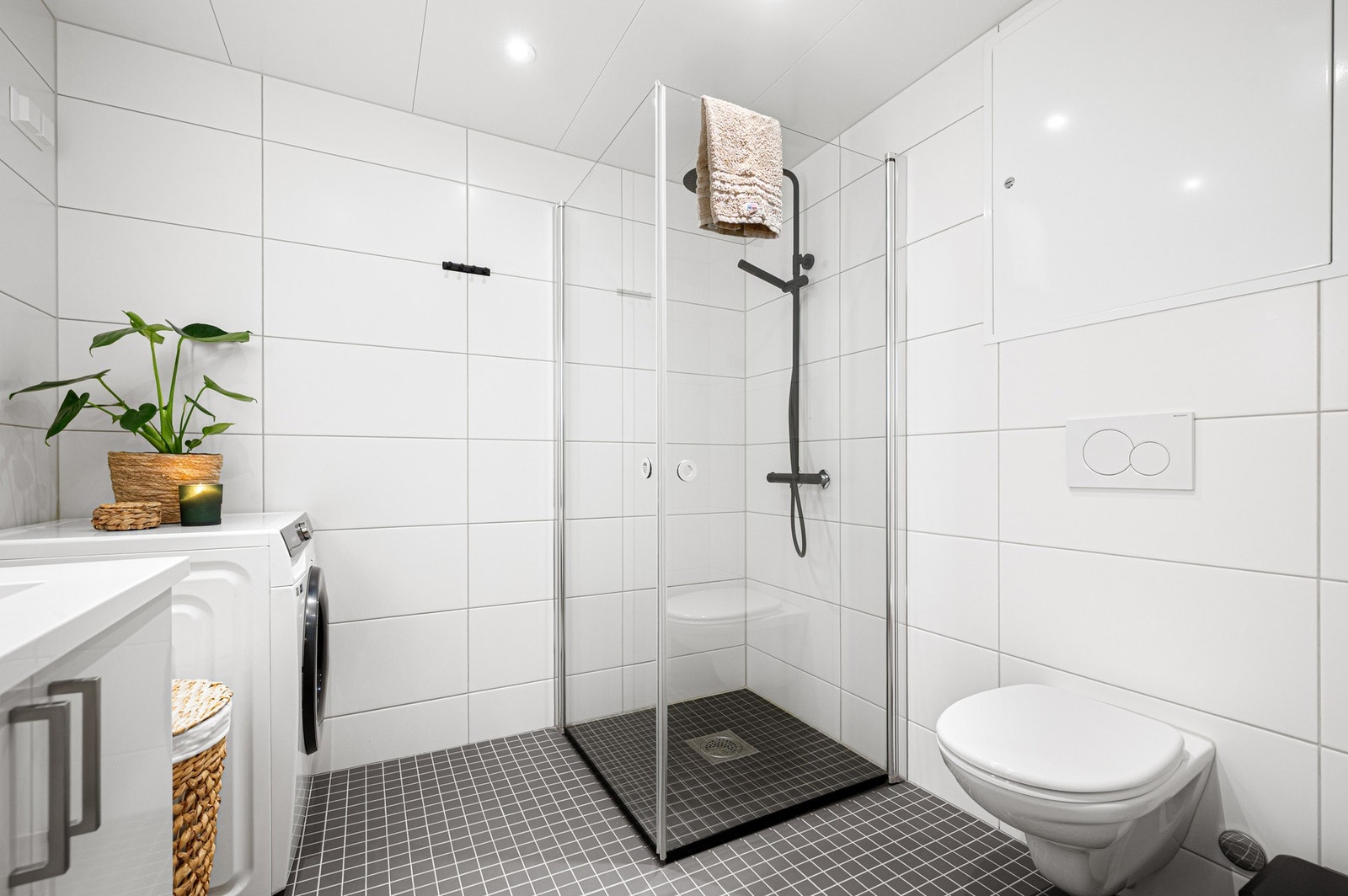 Badet er innredet med dusjhjørne, veggmontert toalett, baderomsinnredning med servant og speil. Galleribilde