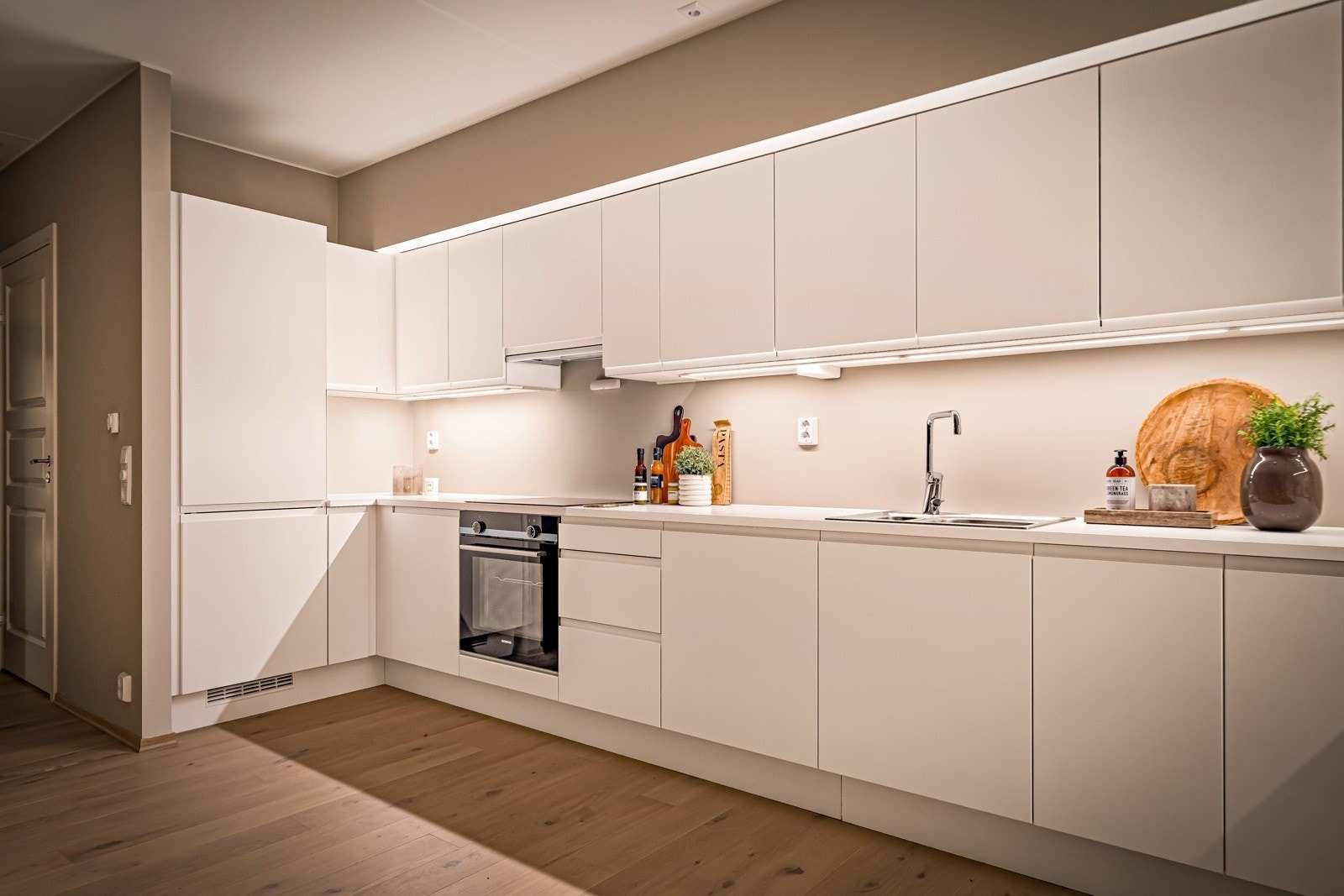 Lekkert kjøkken med glatte fronter og laminert benkeplate med integrert kjøkkenkum Galleribilde