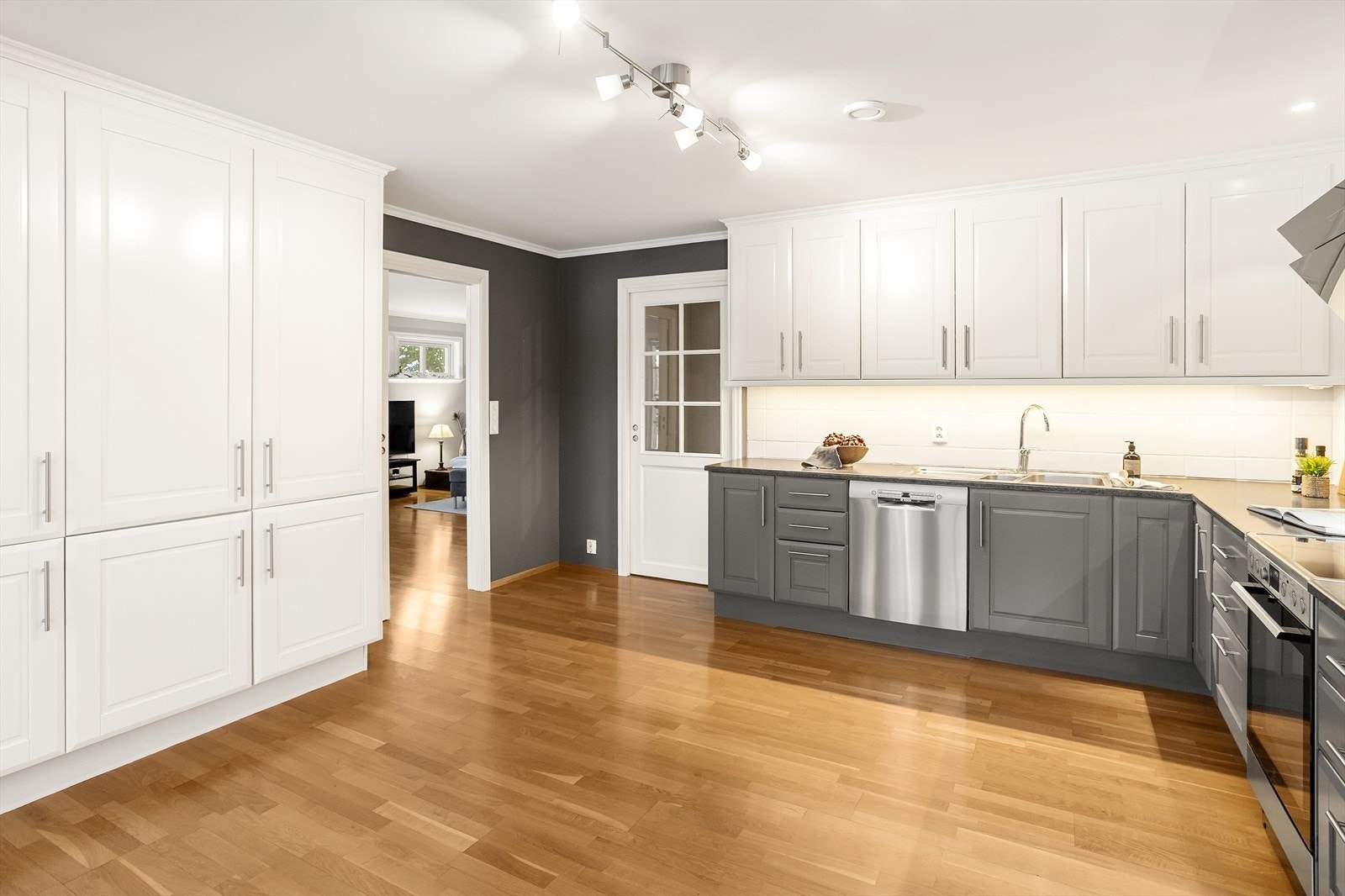 Kjøkkenet har mye benkeplass, grå profilerte fronter og benkeplate av laminat med fliser over benkeplate. Galleribilde