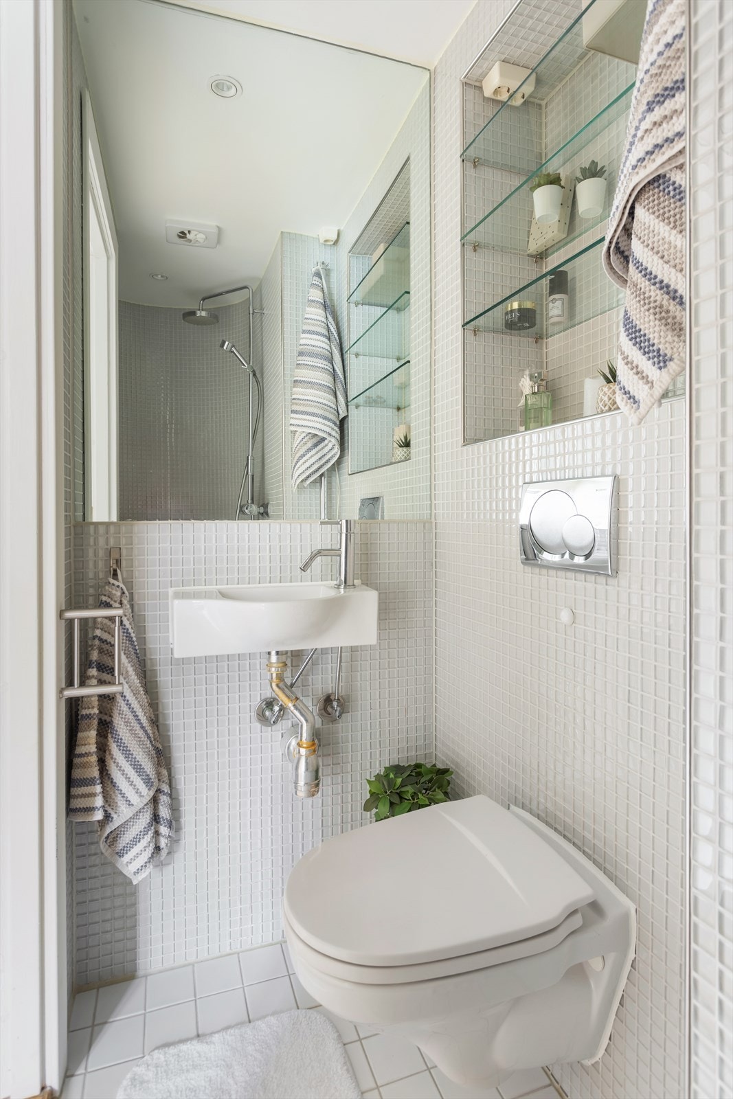 En innfelt hylle med glassplater og et speil gir praktisk oppbevaringsplass for toalettartikler. Galleribilde