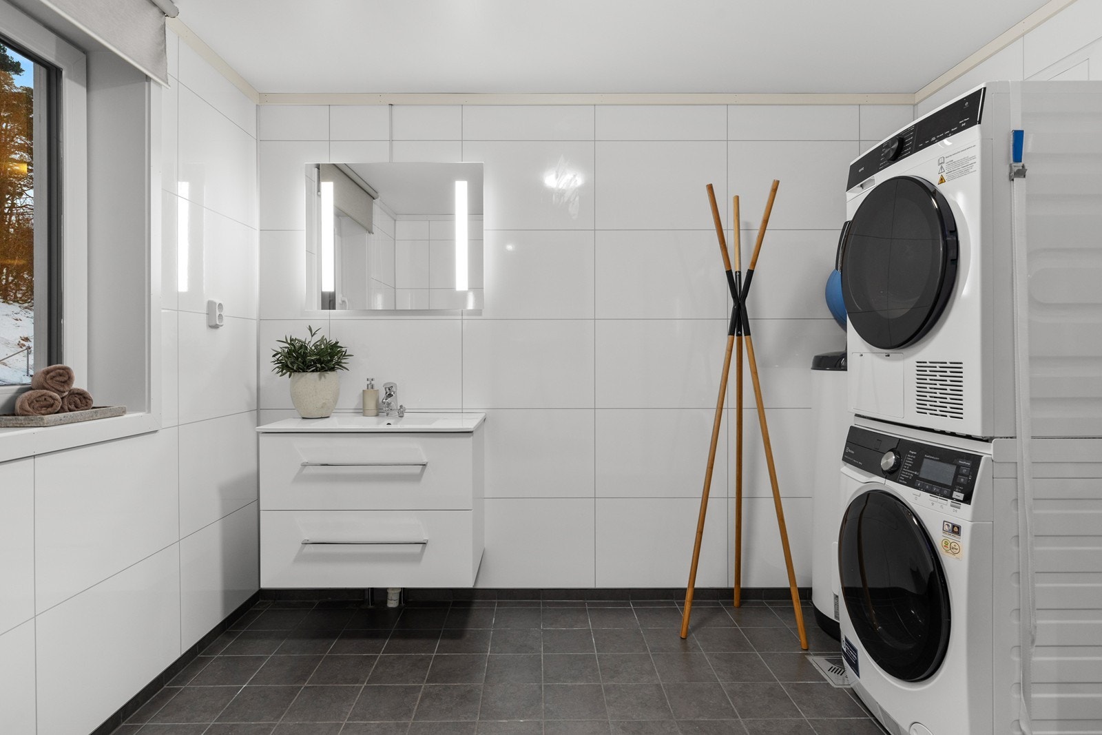 Pent hovedbad med flislagt gulv og varmekabler. Våtromsplater på vegger. Skuffinnredning med speil, samt opplegg for vaskemaskin/tørketrommel. Galleribilde