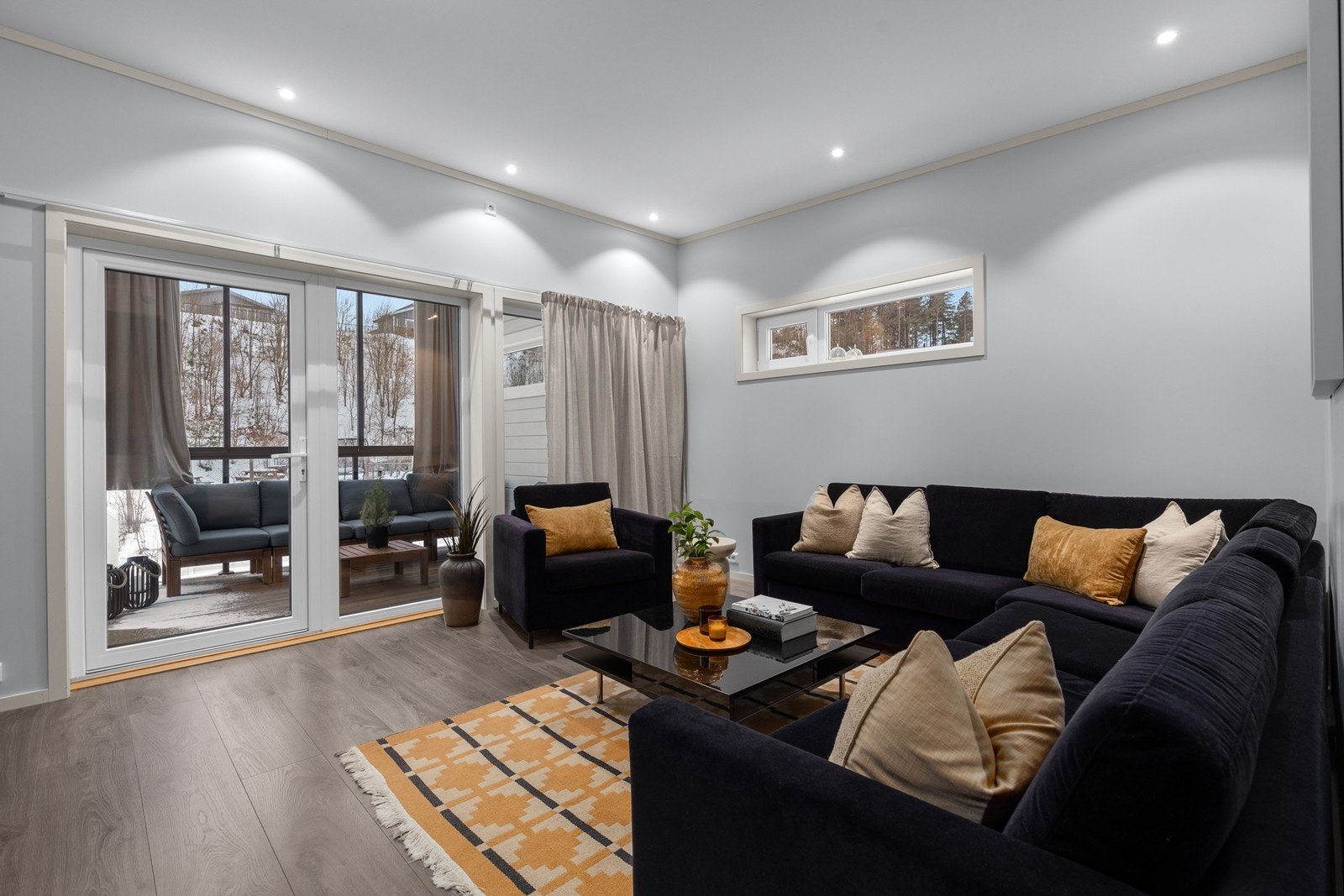 Lun stue med spotlights i tak, og utgang til innglasset balkong Galleribilde