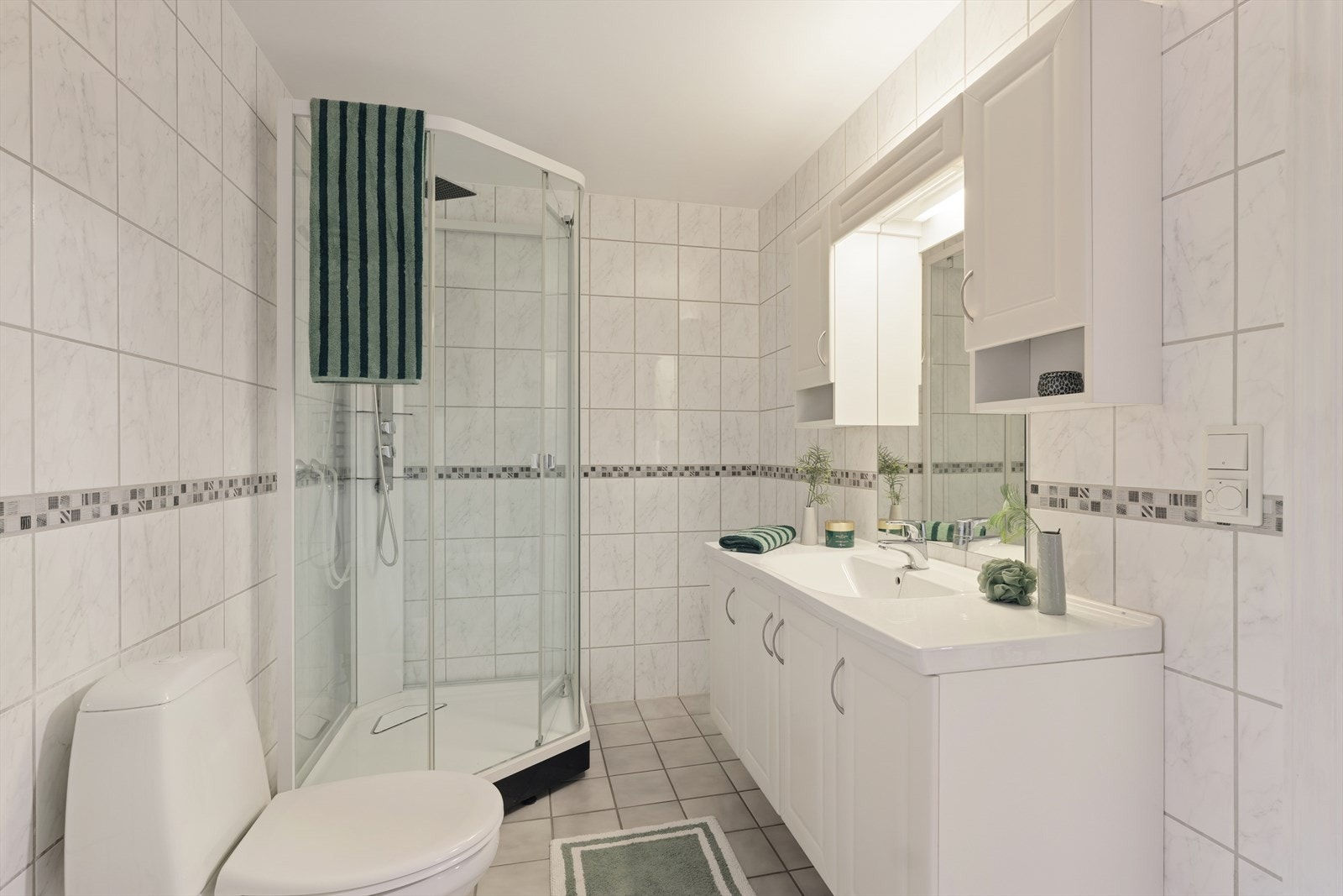 Badet er utstyrt med dusjkabinett, servant, toalett, servantskap samt opplegg for vaskemaskin Galleribilde