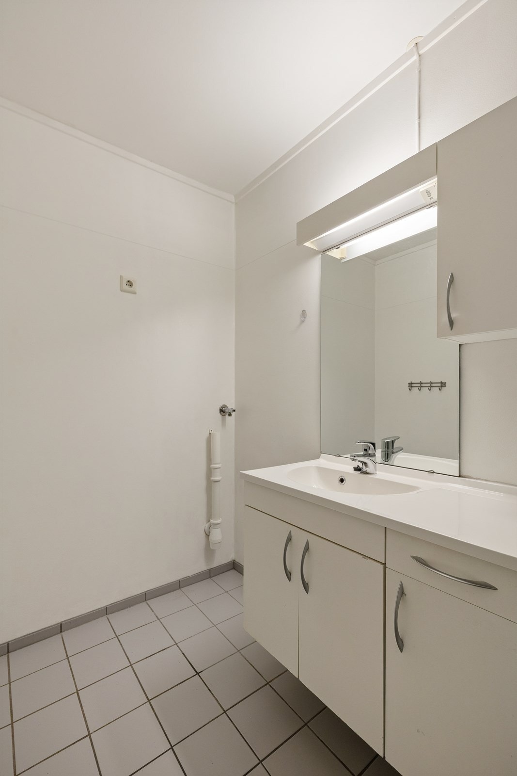 Videre inneholder badet et gulvmontert toalett, dusjhjørne med herdet glass og opplegg for vaskemaskin. Galleribilde