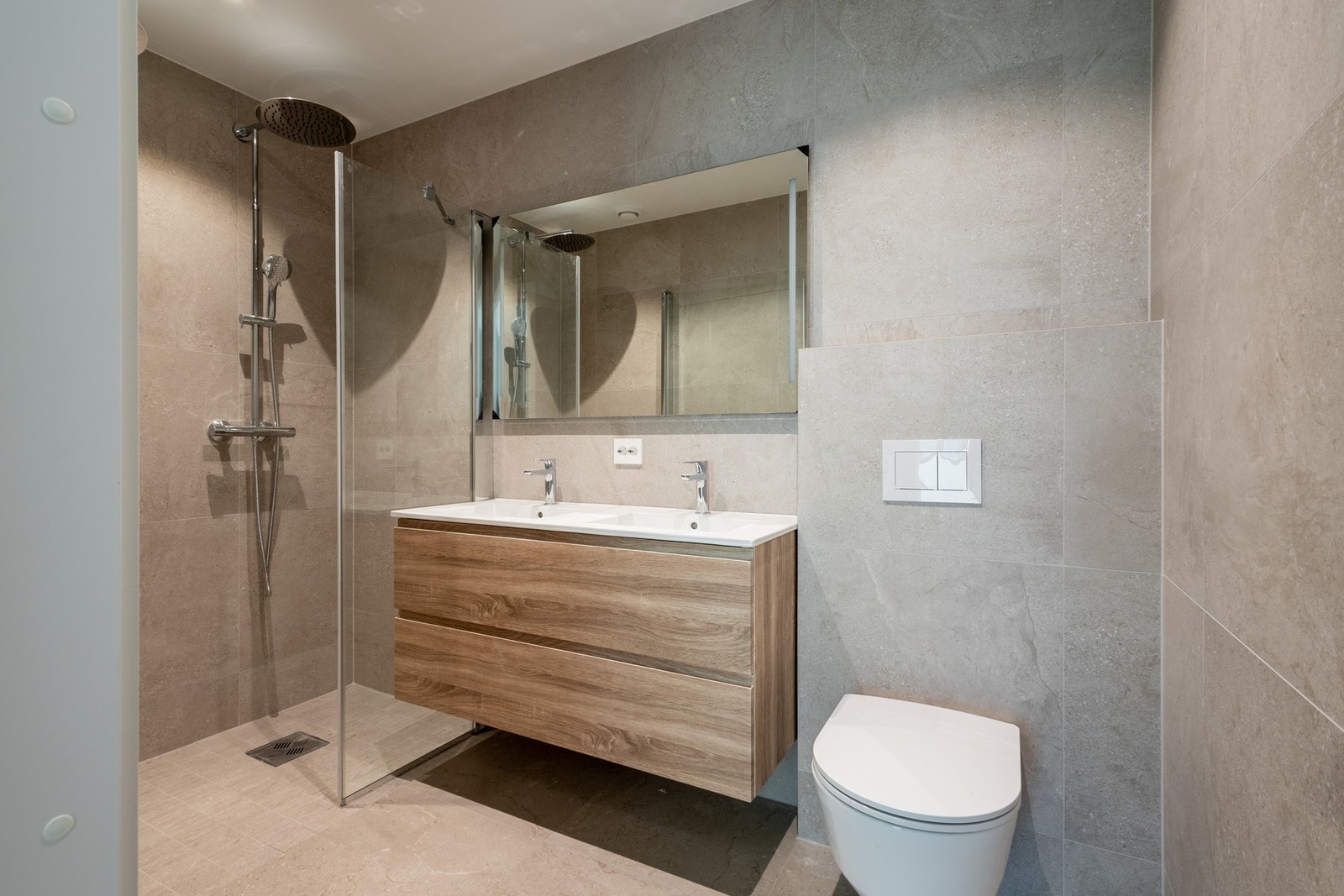 Moderne servantinnredning med vask og speil, samt badekar og dusjhjørne med regnfallsdusj - en perfekt kombinasjon av stil og funksjonalitet. Galleribilde