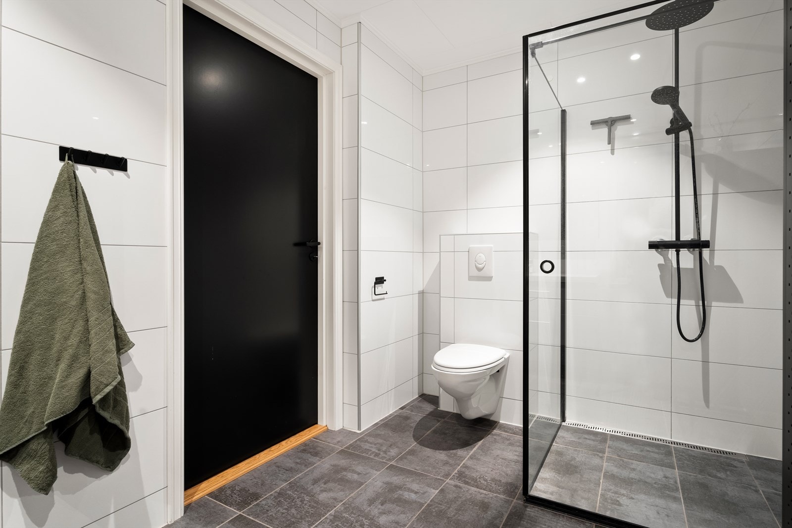 Vegghengt toalett og dusjhjørne med moderne armatur gir et stilrent uttrykk. Galleribilde