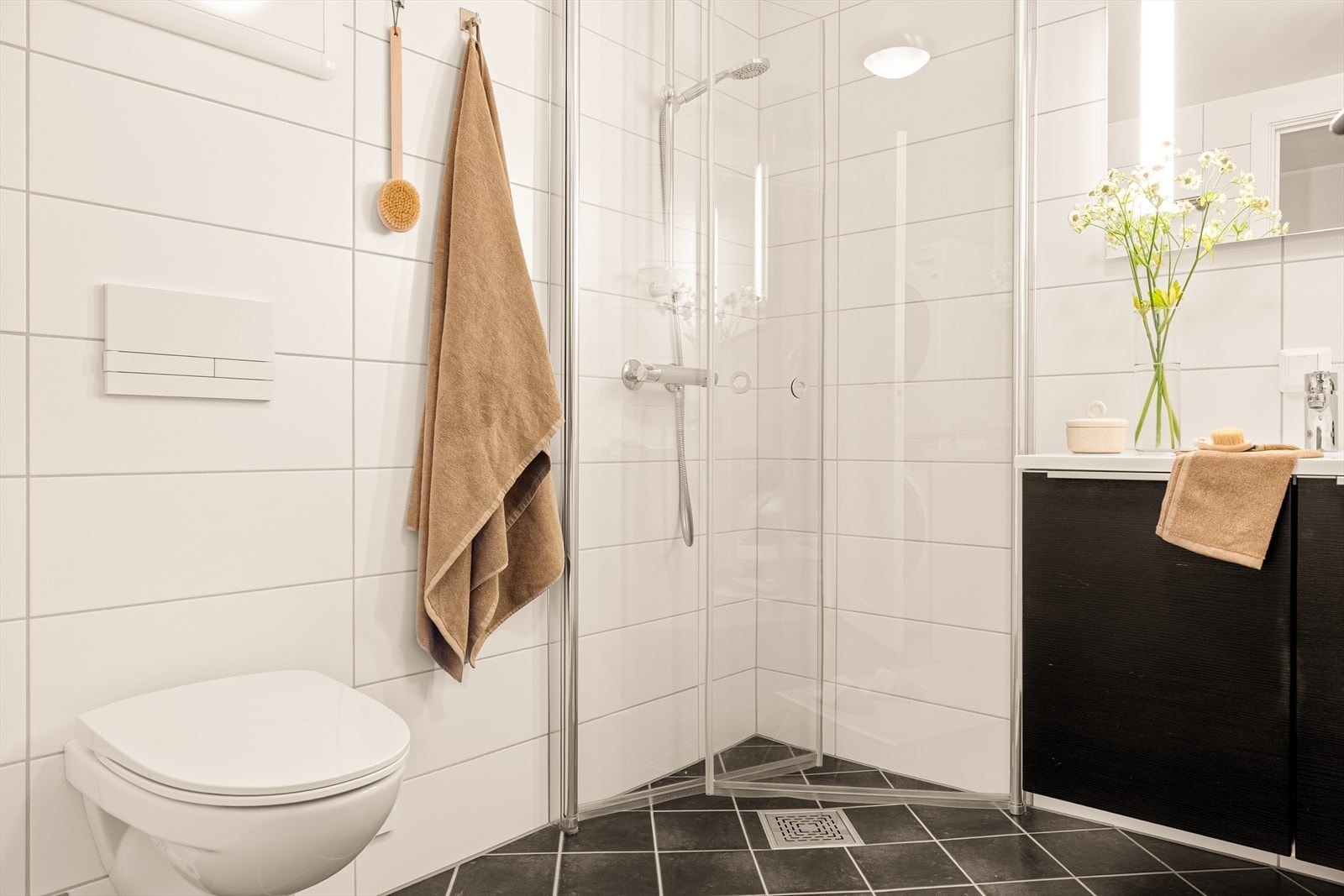 Badet har et ryddig og tidløst uttrykk, med flislagte overflater i nøytrale toner som gir rommet et rolig og balansert preg. Galleribilde