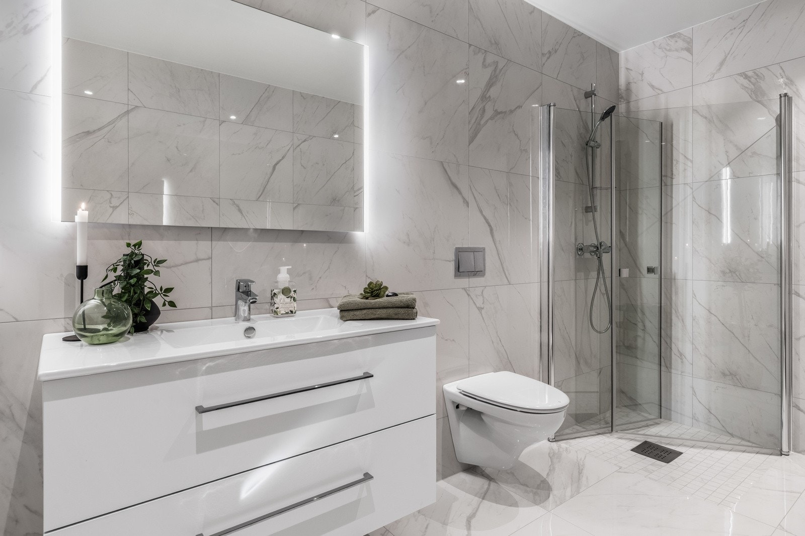 Hovedbadet nede er lyst og luftig, med store, lysegrå fliser i stilrent marmormønster. Galleribilde