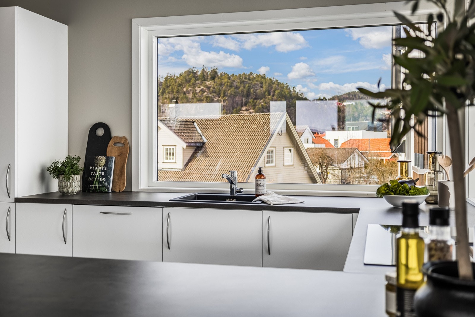 Innredningen er fra Alfa3, med hvite, glatte fronter, vitrineskap og oppvaskkum nedfelt i en mørk benkeplate av laminat. Galleribilde