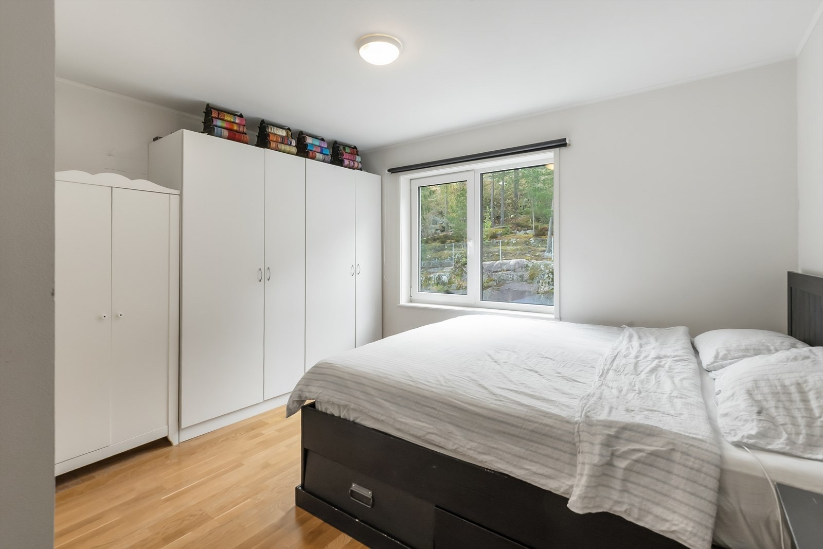 Lyst soverom med plass til stor seng og garderobeskap Galleribilde