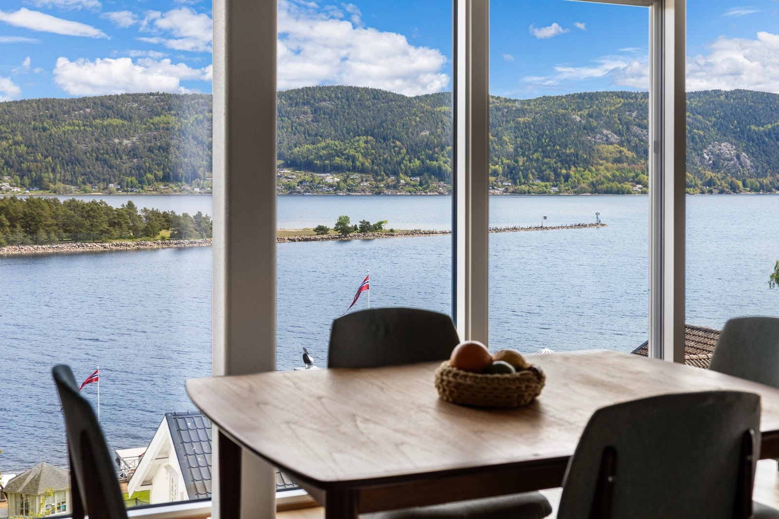 Store vinduer med utsikt over fjord og skogkledde åser. Galleribilde