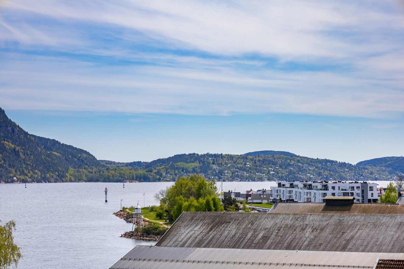Utsikt over fjord, åser og moderne bebyggelse. Galleribilde