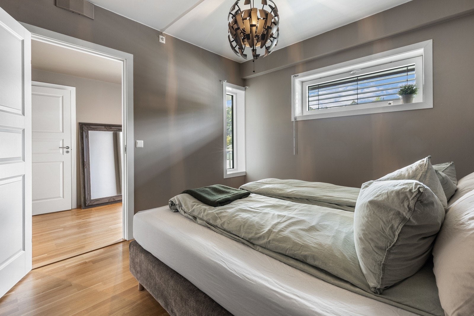 Soverom med dobbeltseng, store vinduer og lys innredning. Galleribilde