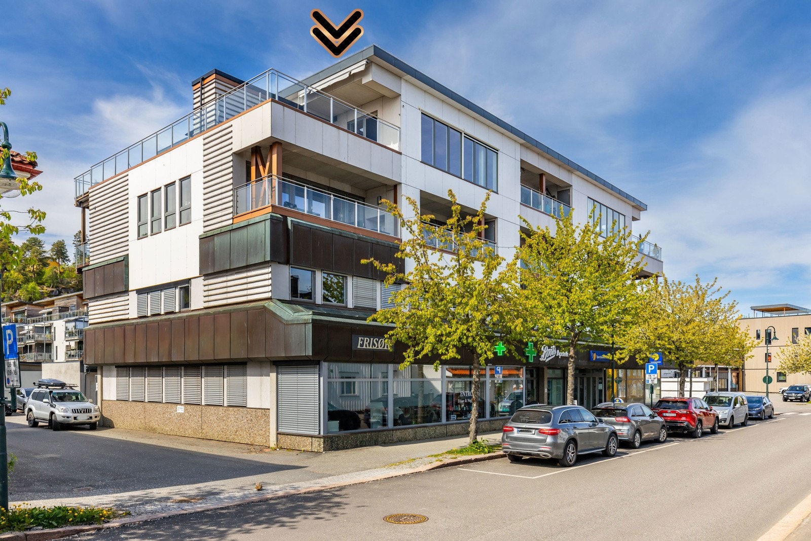 Moderne bygning med næringslokaler i første etasje og leiligheter med store vinduer og balkonger. Galleribilde