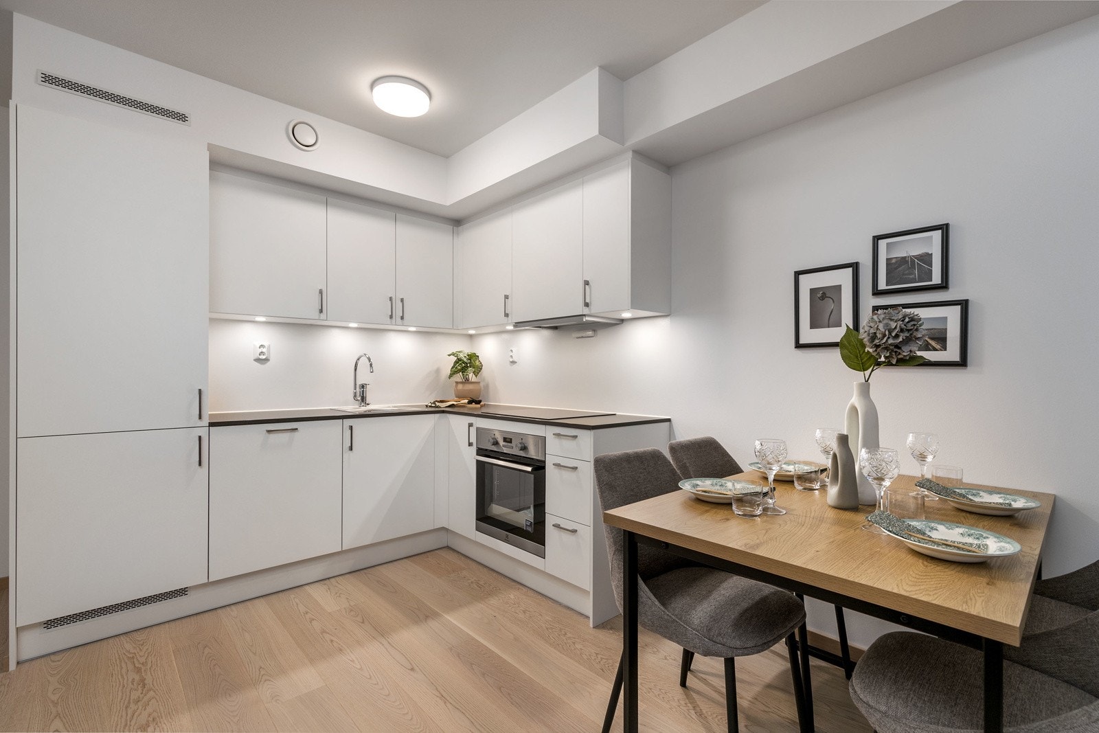 Lekkert kjøkken i åpen løsning mot stue, med integrerte hvitevarer. Kjøkkenet har en praktisk hjørneløsning, som gir rikelig av skap og benkeplass. Bilde fra L406. Galleribilde