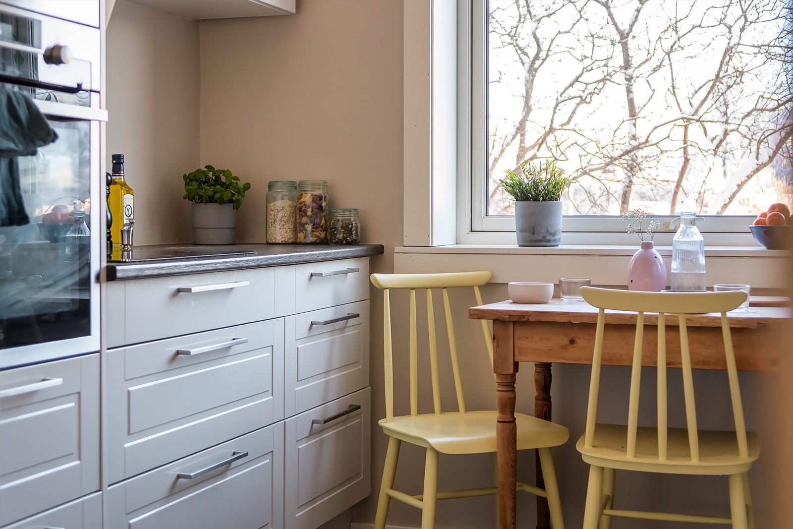 Kjøkkenet har stilren innredning med hvite, profilerte fronter og laminert benkeplate Galleribilde