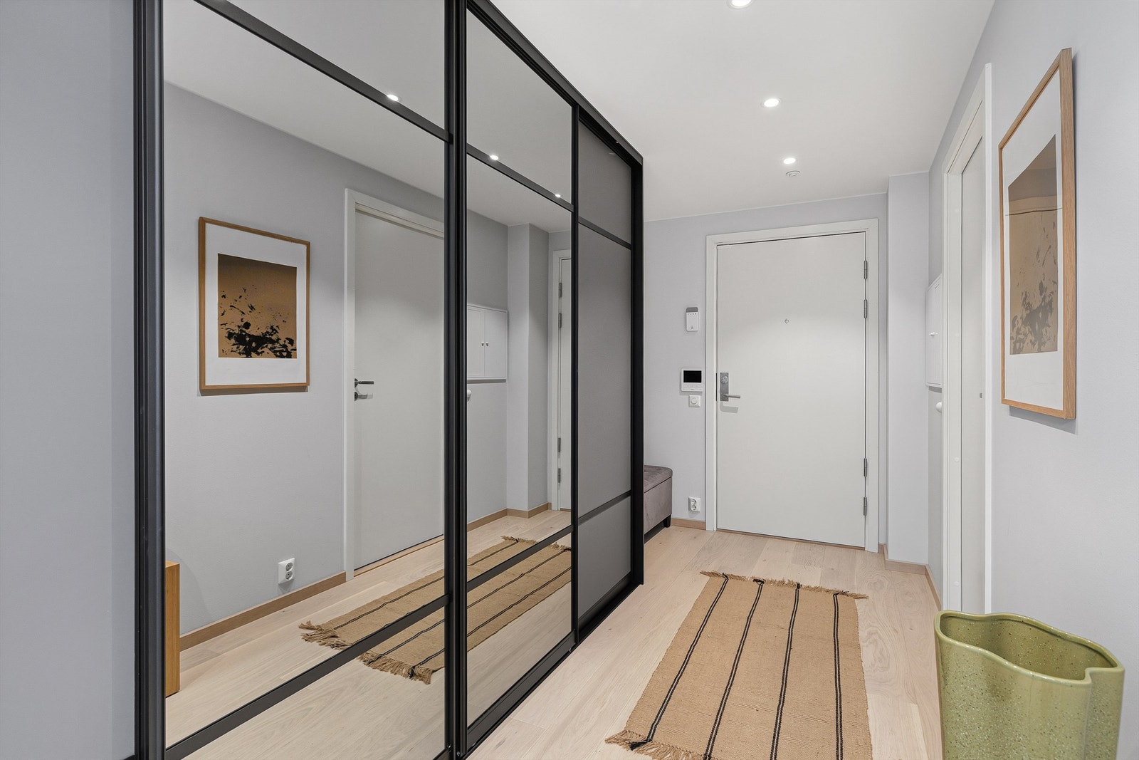 Du blir tatt i mot i en svært romslig gang med skyvedørsgarderobe fra garderobemekka hvor du kan henge fra deg klær og sette fra deg sko. Du har også plass til en benk. Galleribilde