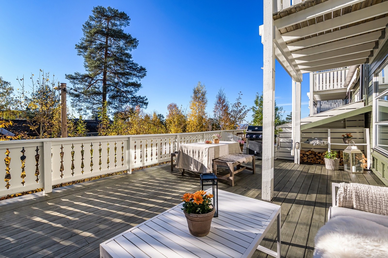 Terrassen har terrassebord fra 2019 på gulv og lysmalt rekkverk av tre. Galleribilde