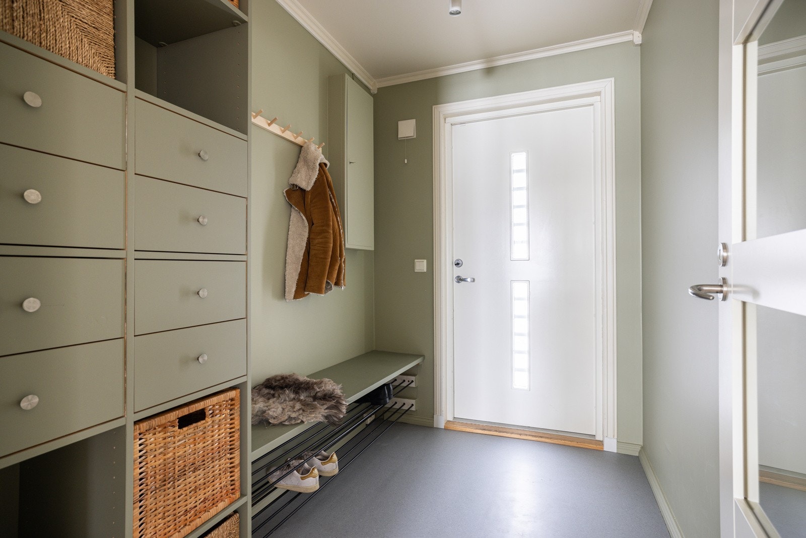 Når du entrer boligen, kommer du inn i en innbydende og praktisk entré med belgg på gulv og glatte overflater malt i en fin grønnfarge. Galleribilde